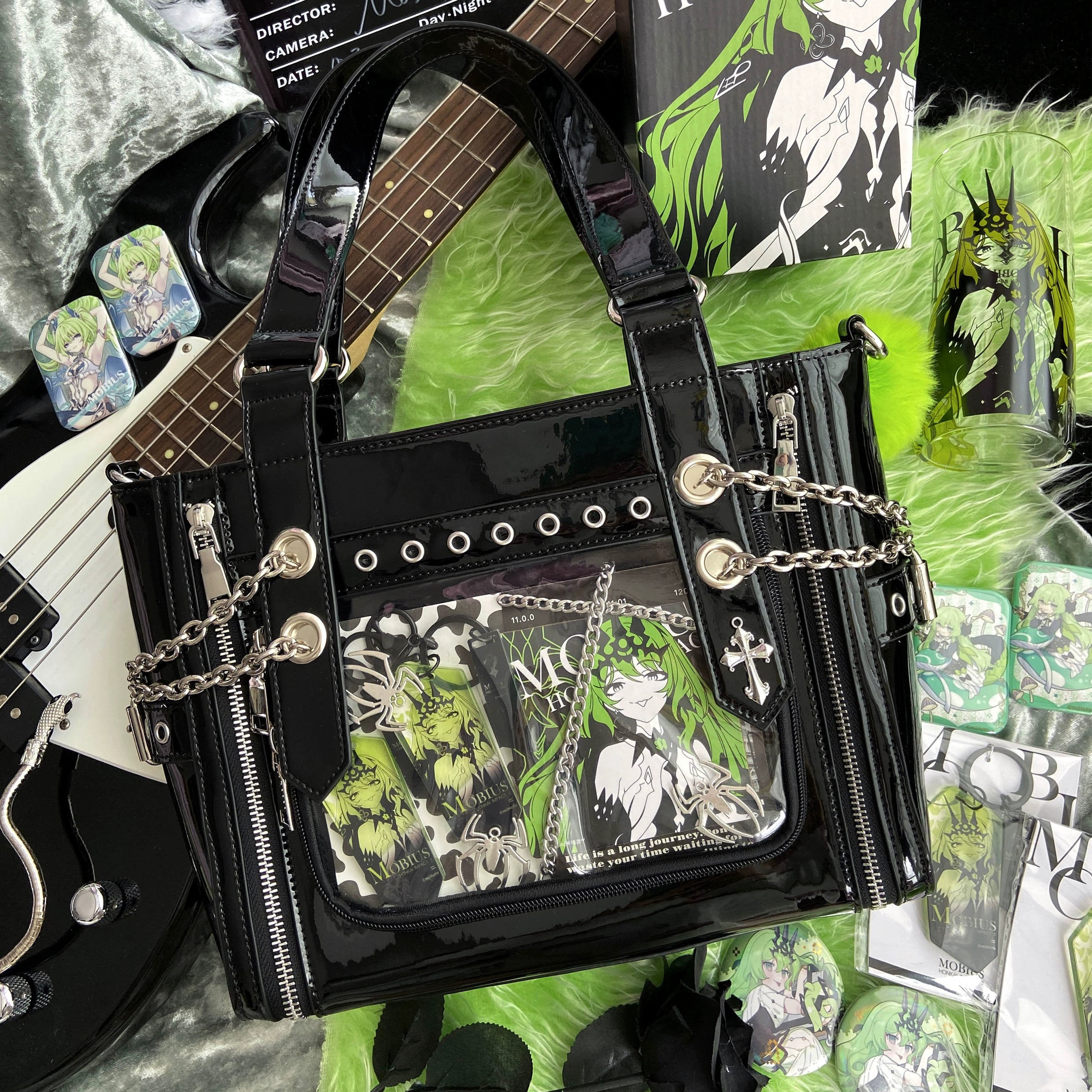 Black patent leather Jirai Kei ita tote bag with metal chains green anime display inserts and rivet details in studio