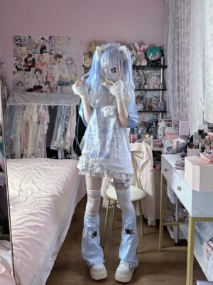 Tenshi Kaiwai blue and white anime graphic short sleeve t-shirt worn by blue twin-tail model in pink otaku bedroom with full body mirror selfie front view showing cute kawaii aesthetic Jirai Kei style