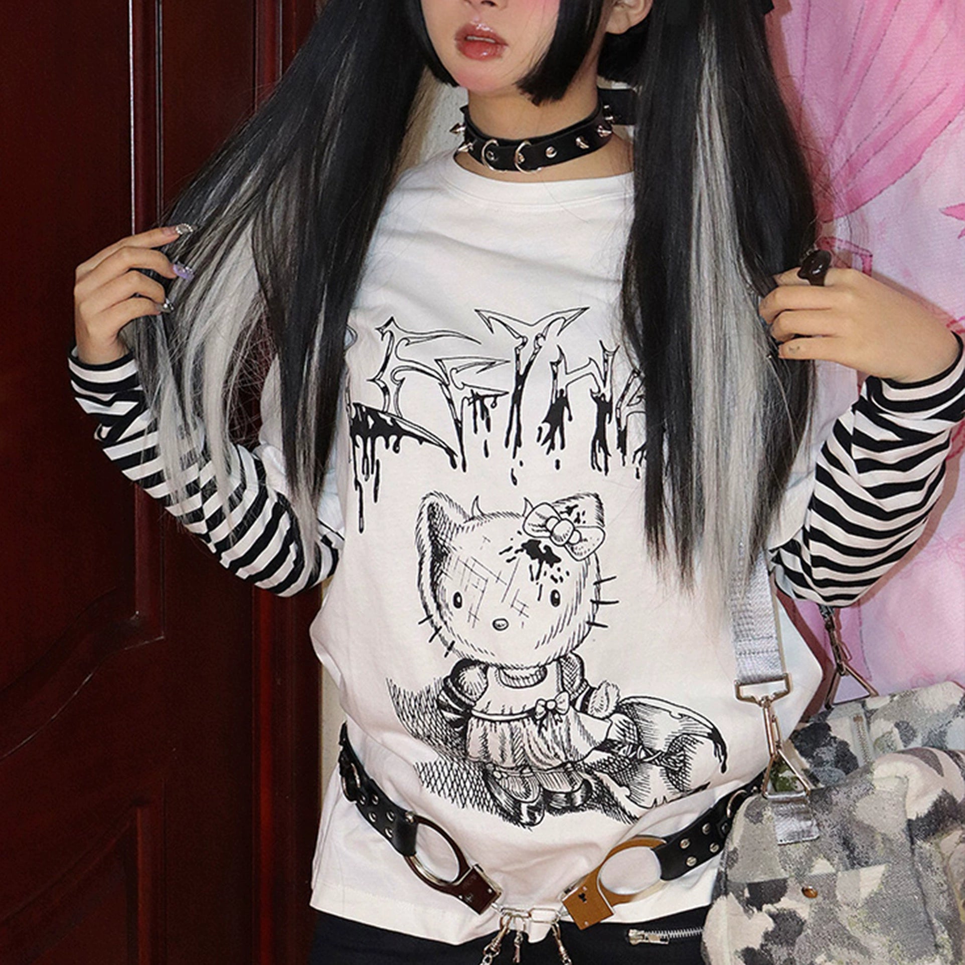 Half-body front shot of white-base jirai kei fake two-piece tee with black-white striped sleeves, damaged cat cartoon print, worn with gothic choker and long dark hair