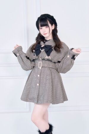 Brown plaid Jirai Kei cape trench coat with detachable black bow collar and adjustable waist belt worn by model in front studio view