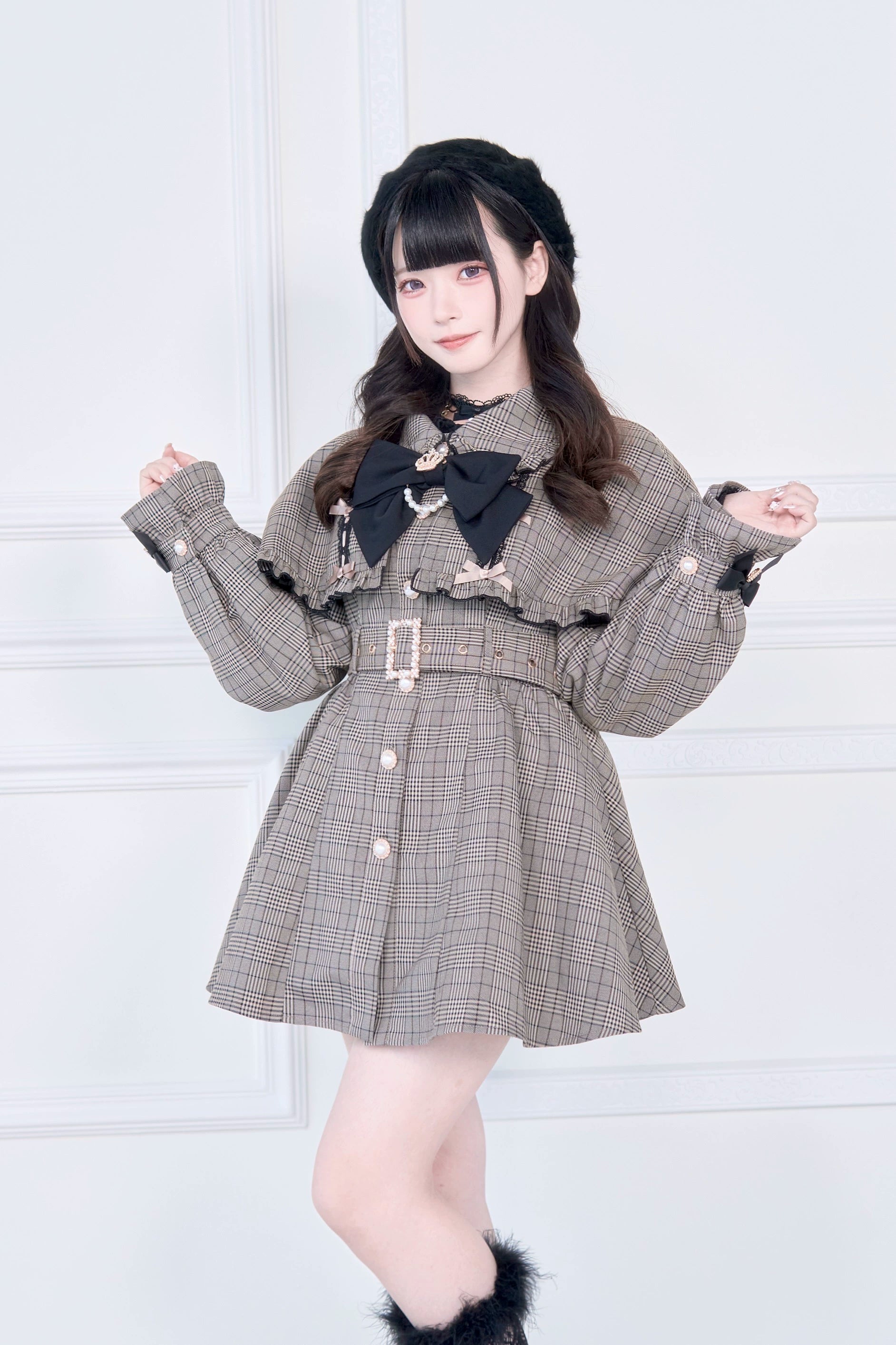 Brown plaid Jirai Kei cape trench coat with detachable black bow collar and adjustable waist belt worn by model in front studio view