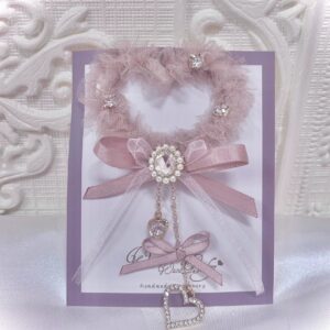 Pink heart-shaped tulle hair clip with rhinestones and satin bow featuring heart pendant charm, displayed on branded card