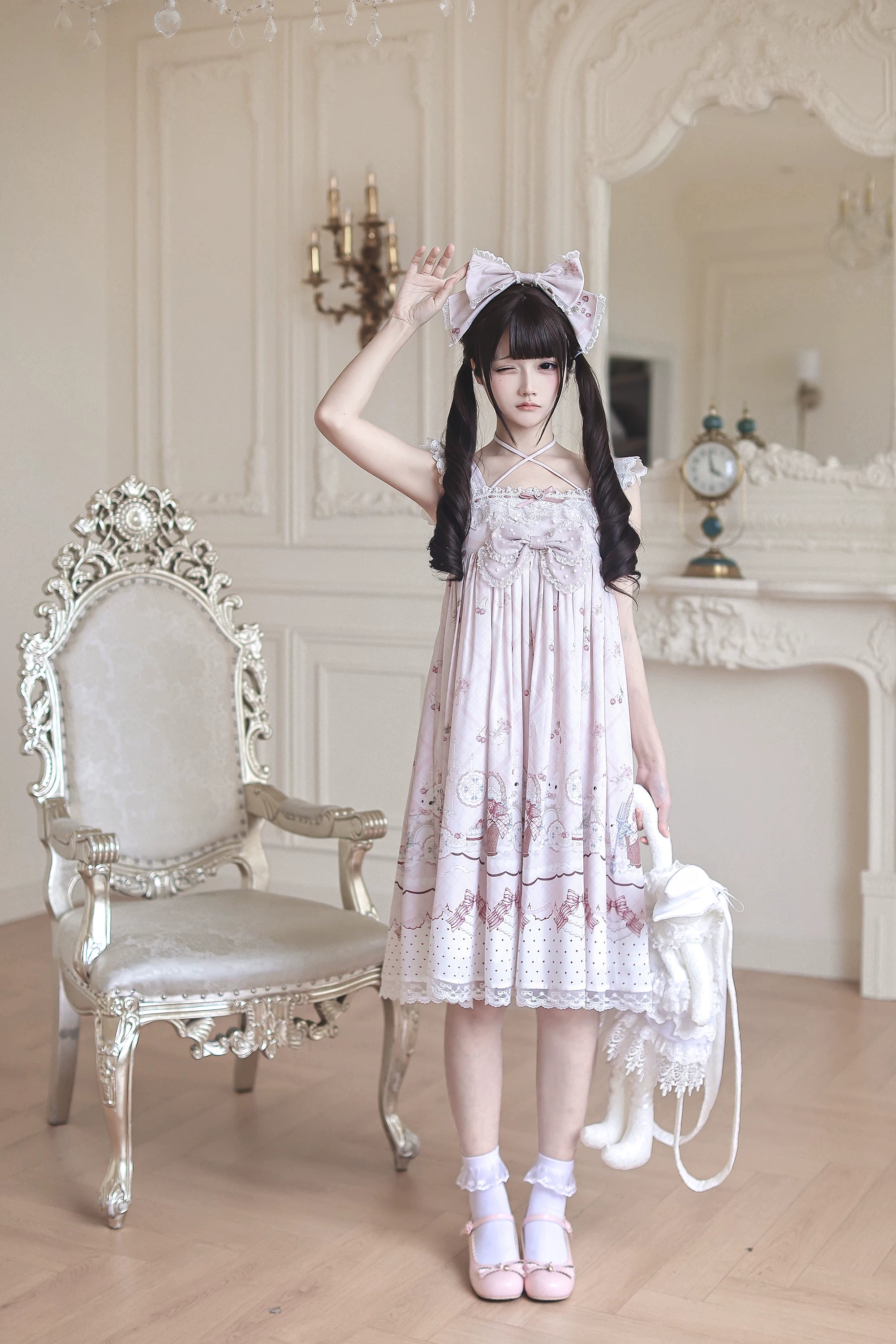 Front full-body view of strawberry bunny Jirai Kei Lolita dress in European room setting showing ruffled halter straps lace rabbit bag and matching hair bow details