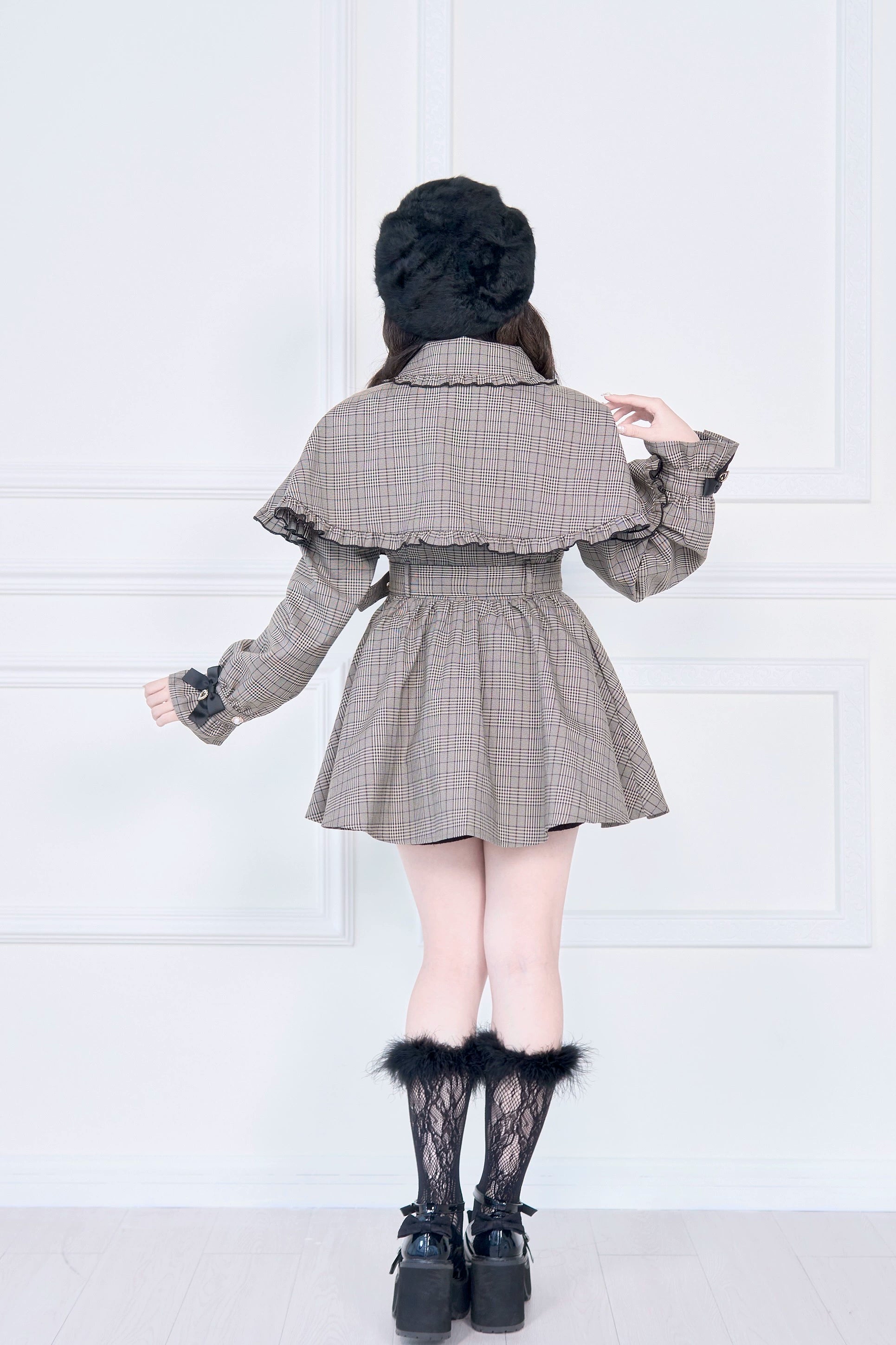 Brown plaid Jirai Kei trench coat back view displaying ruffled cape construction and pleated feminine skirt hem