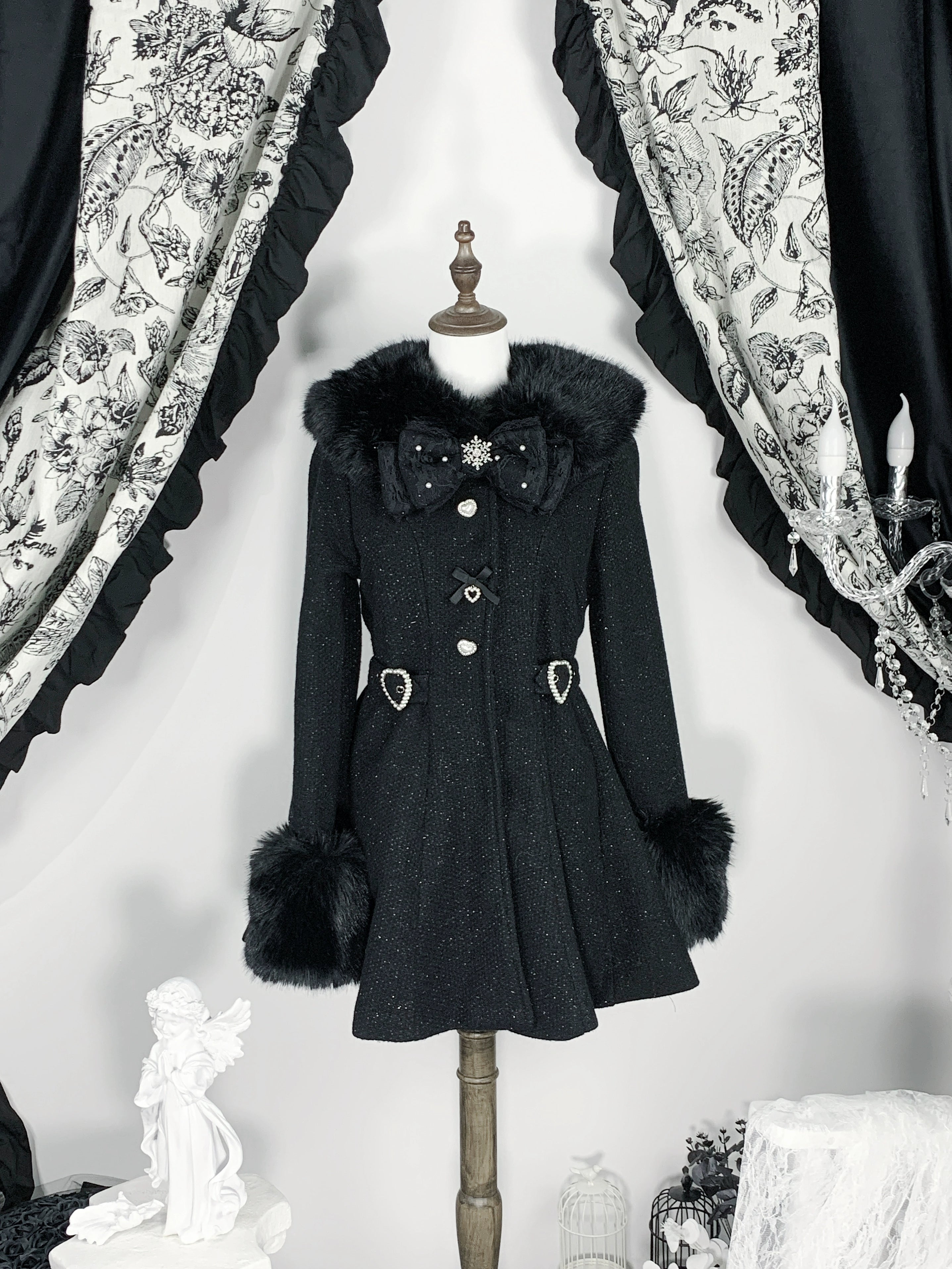 Black Ryousangata Jirai Kei winter coat flat front mannequin display showing tweed fabric faux fur trims bow brooch heart waist accents vintage background