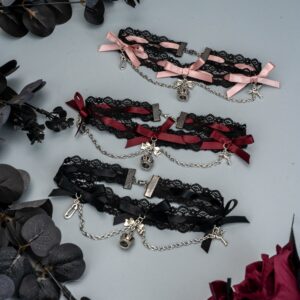 Three Jirai Kei lace bow choker necklaces in black pure black and black pink and black red variants displayed flat lay arrangement with dark foliage and red roses gothic aesthetic jewelry collection