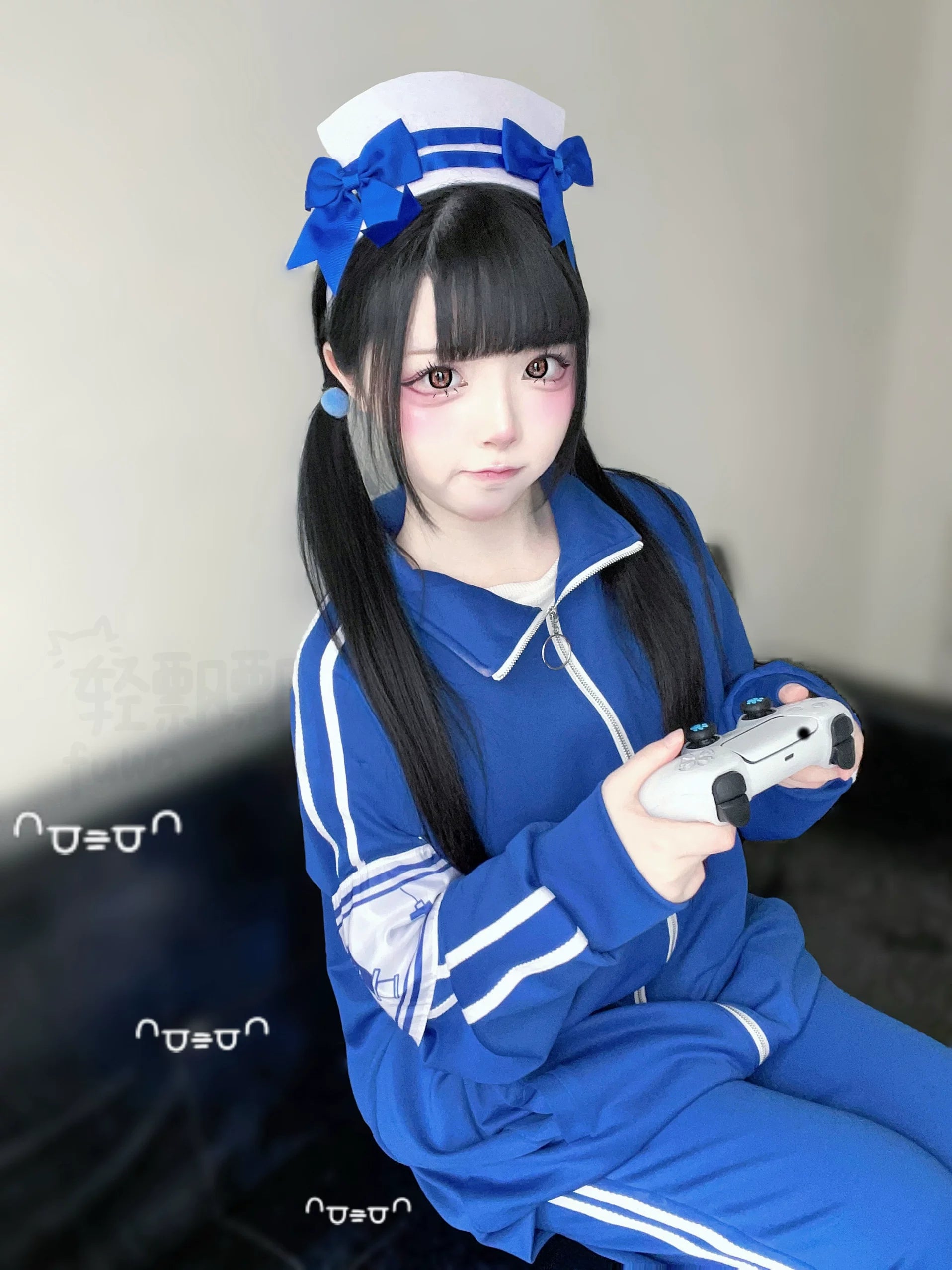 Girl wearing complete royal blue Jirai Kei tracksuit with twin tails and nurse headwear holding game controller indoor