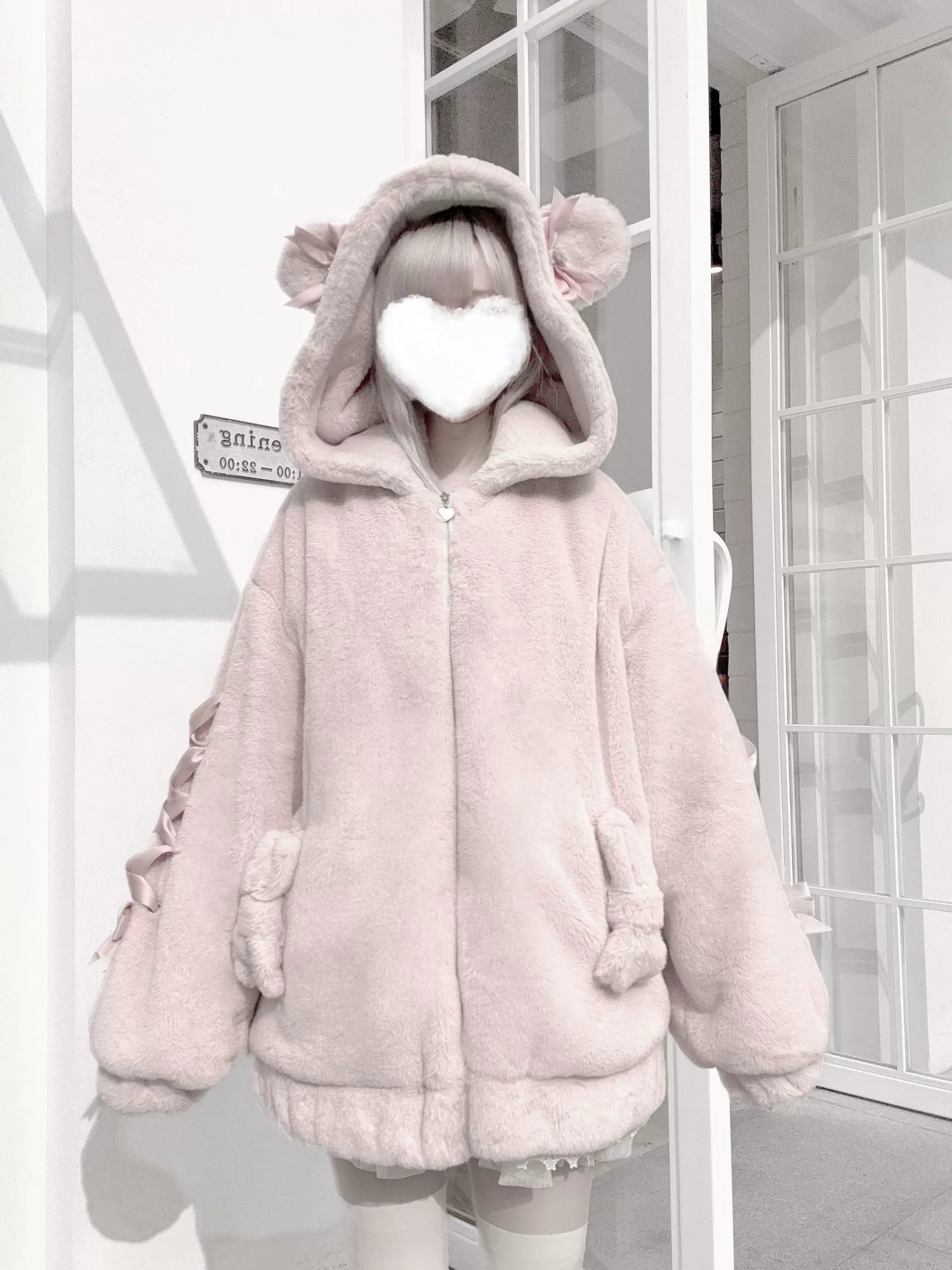 Single model wearing pink Ryousangata bear ear coat with ruffle bow sleeve decorations and loose fit silhouette