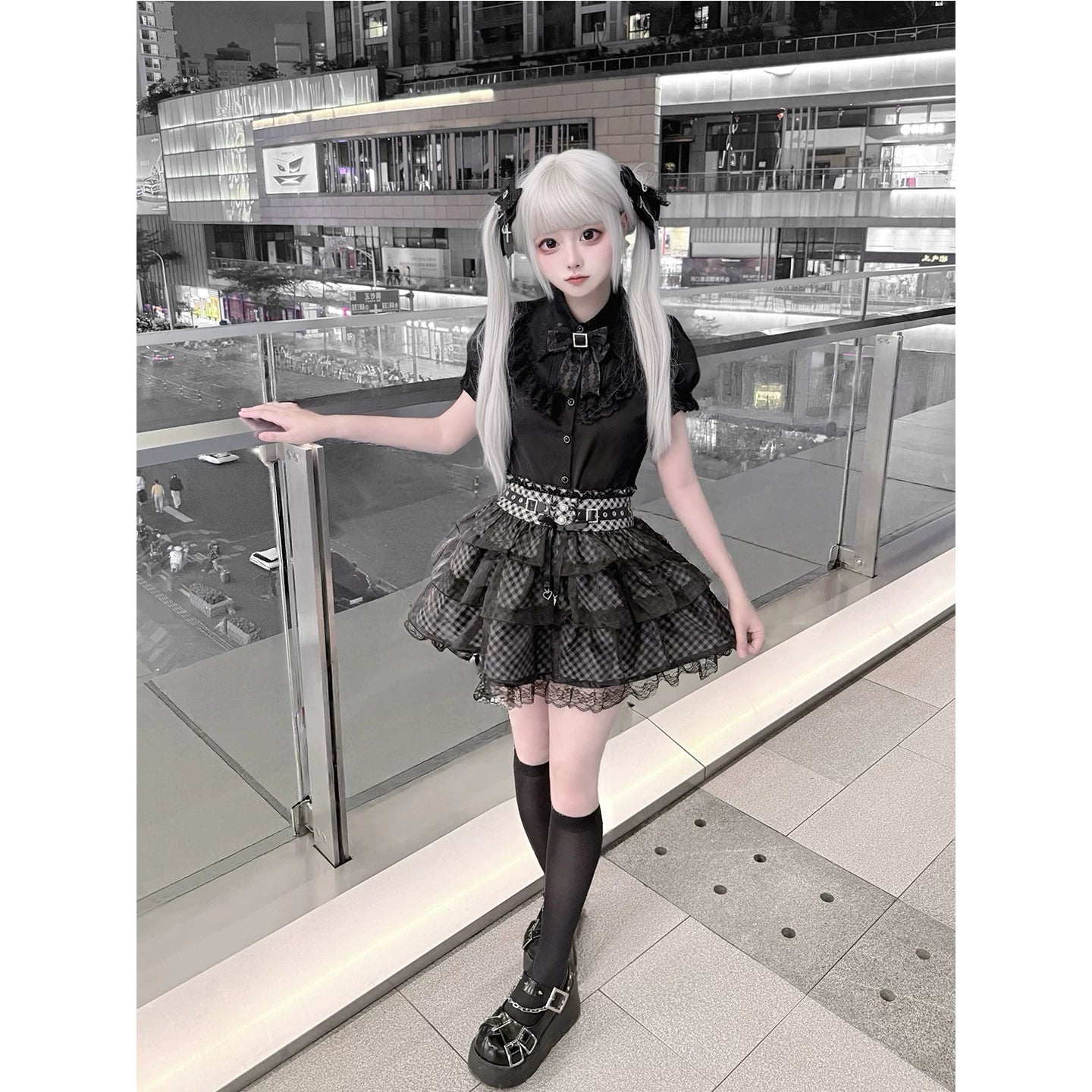 Jirai Kei two-piece outfit front three-quarter view model leaning on railing platform loafers black stockings outdoor mall photography