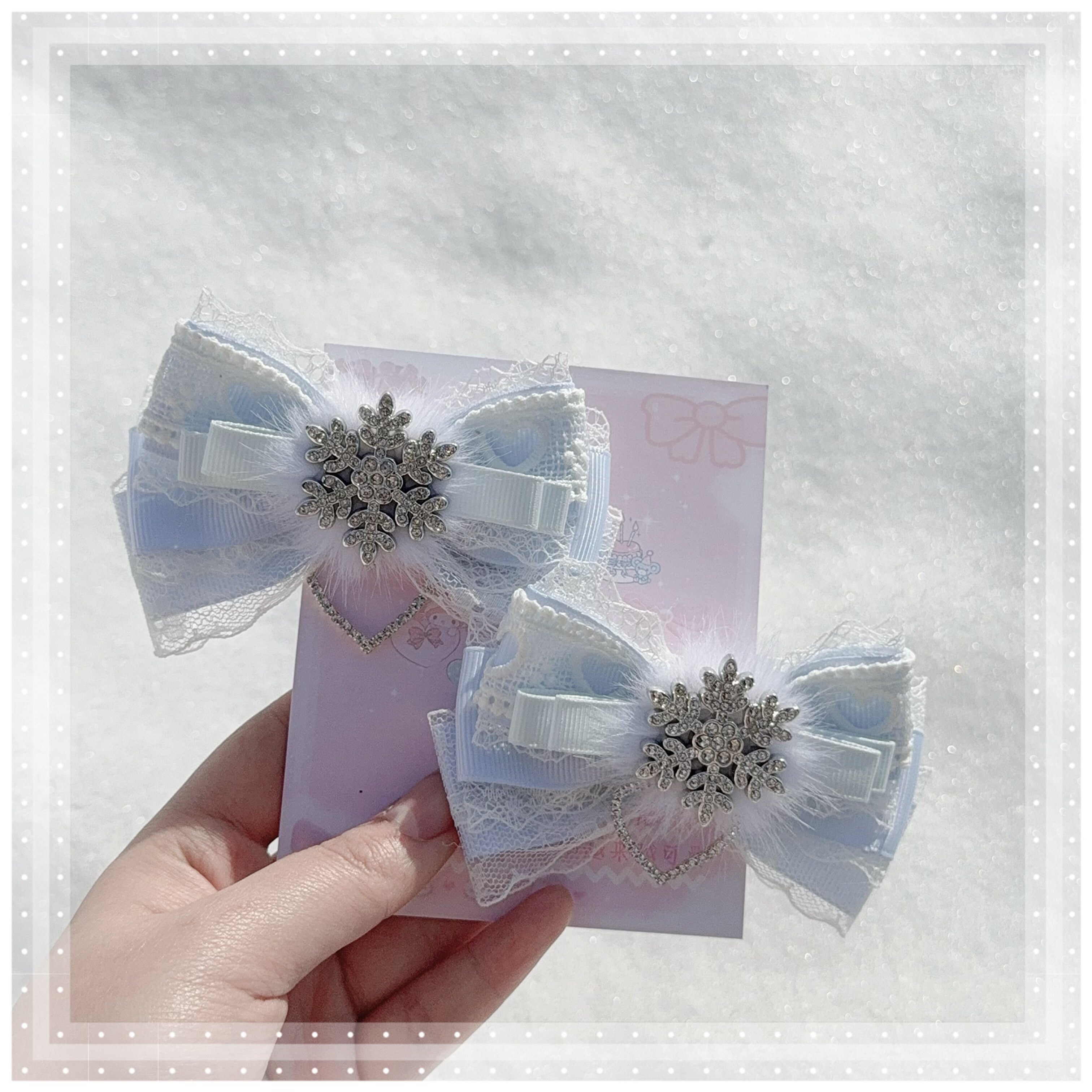 Light water blue Jirai Kei bow hair clips held in hand close-up showing fluffy faux mink fur texture lace detail silver snowflake charm detail