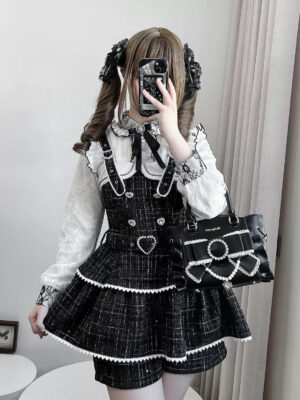 Black tweed Jirai Kei suspender skirt with ruffled trim and heart buckle detail, front mirror selfie view worn by twin-tail model