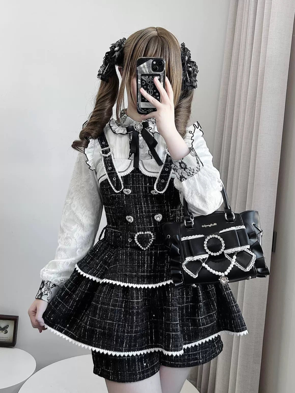 Black tweed Jirai Kei suspender skirt with ruffled trim and heart buckle detail, front mirror selfie view worn by twin-tail model