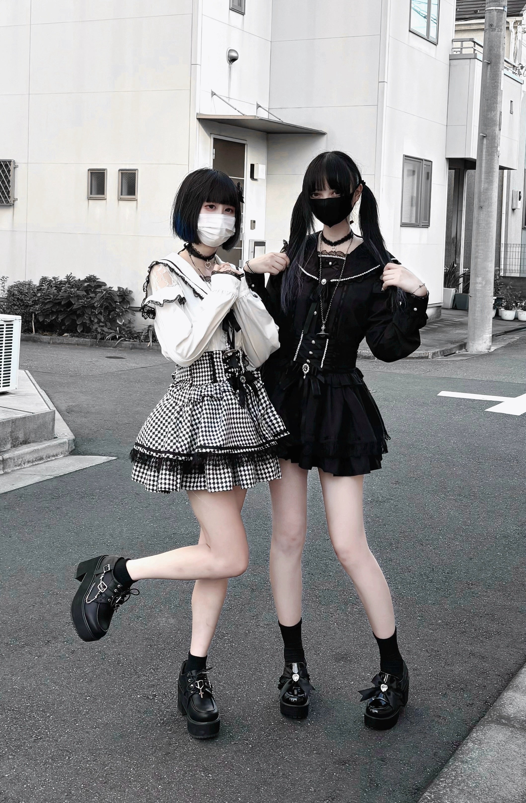 Two masked female models wearing white Jirai Kei sailor collar blouses paired with gingham pleated mini skirts, black platform shoes, and dynamic street fashion poses showing alternate styling approaches