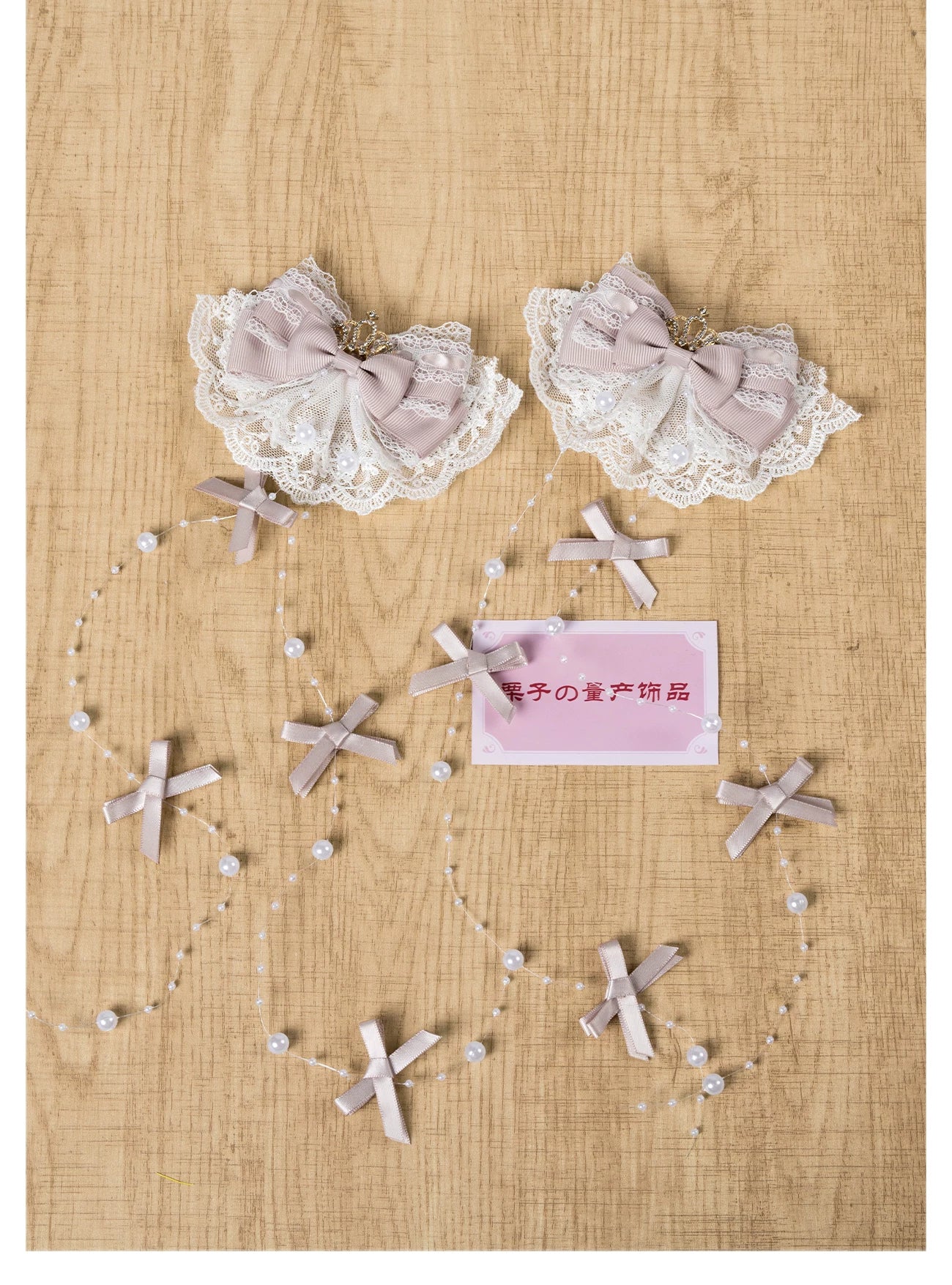 Flat lay display of pastel Jirai Kei hair clip with pink-white lace bow and cross decorated pearl chains on wooden desk
