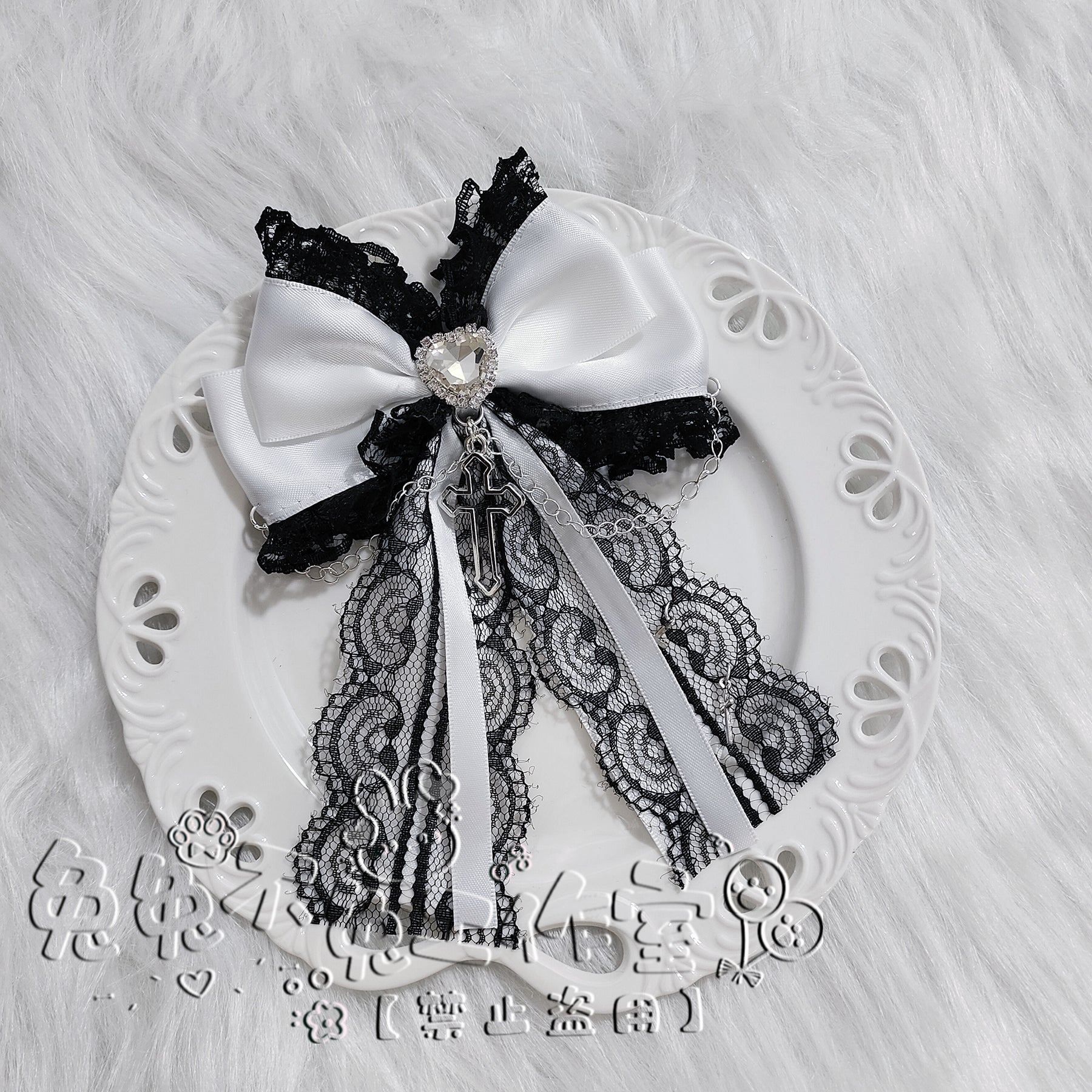 Black-white dual-tone bow hair clip on ceramic plate showing satin bow lace edge round rhinestone center and silver cross pendant chain