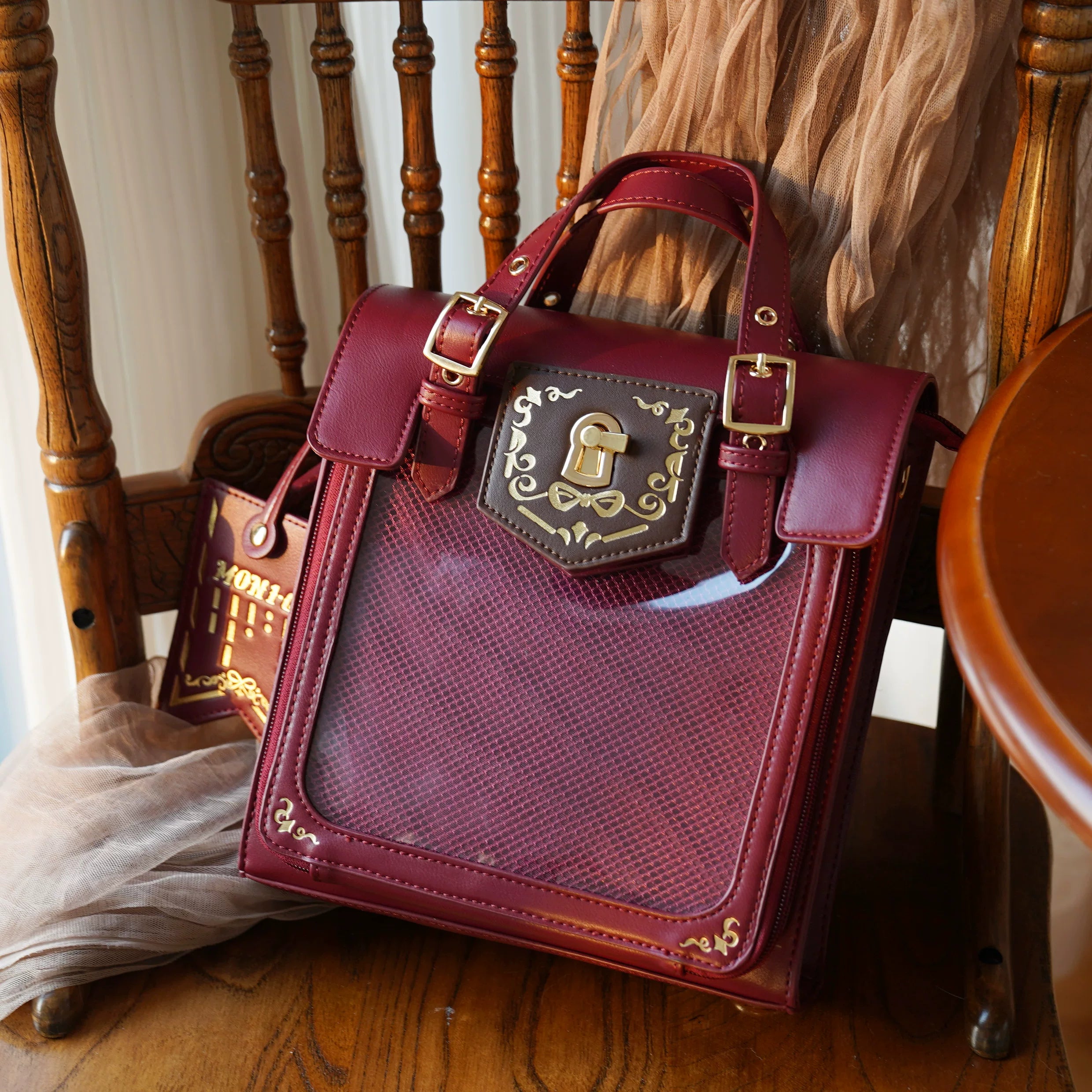 Burgundy luxury vintage Jirai Kei ita satchel bag with jewel tone leather and romantic Tenshi aesthetic, clear window displaying precious anime badge collection