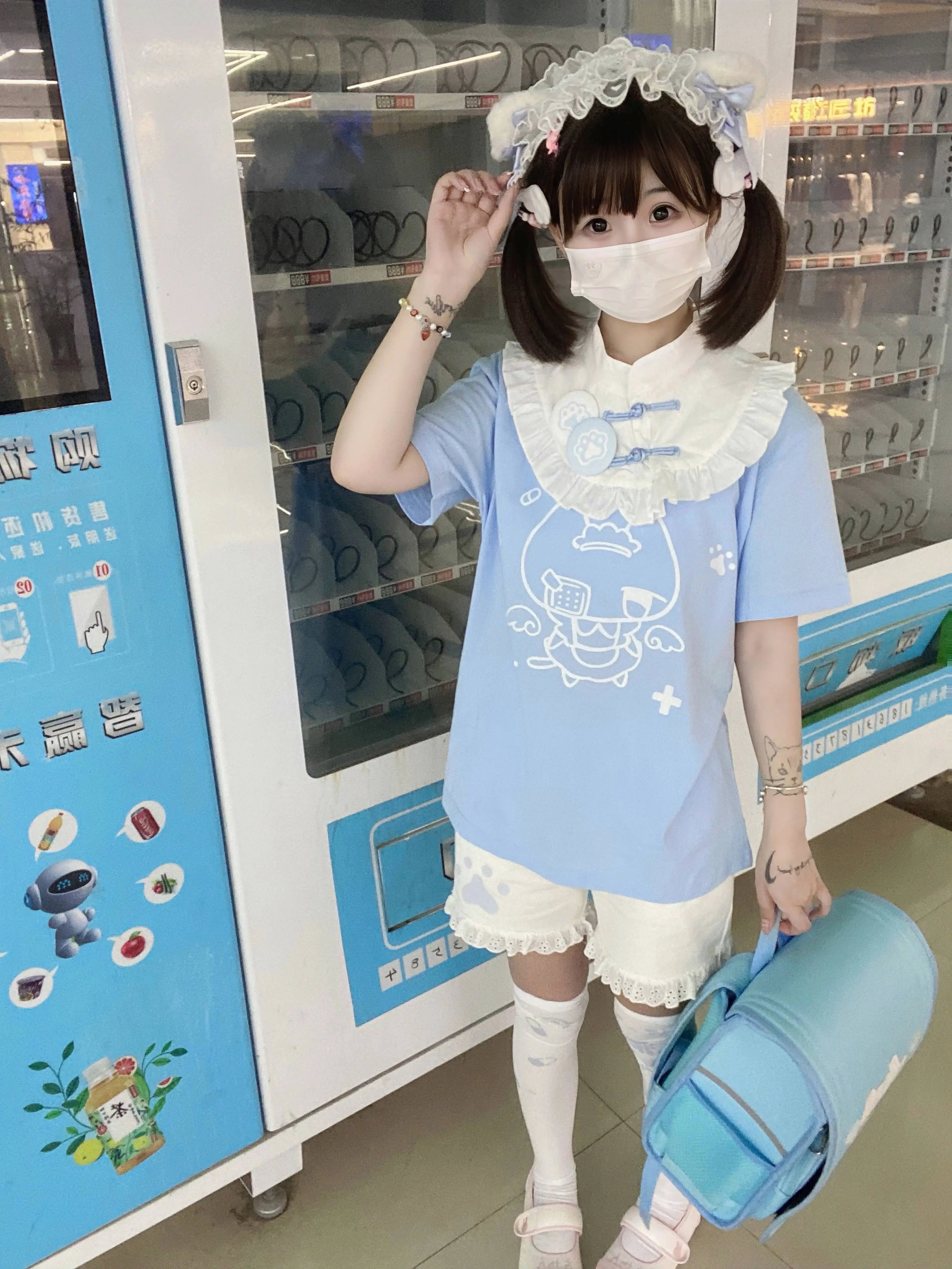 Pastel blue Tenshi Kaiwai cotton T-shirt with blue decorative buttons white ruffled collar three-quarter left angle