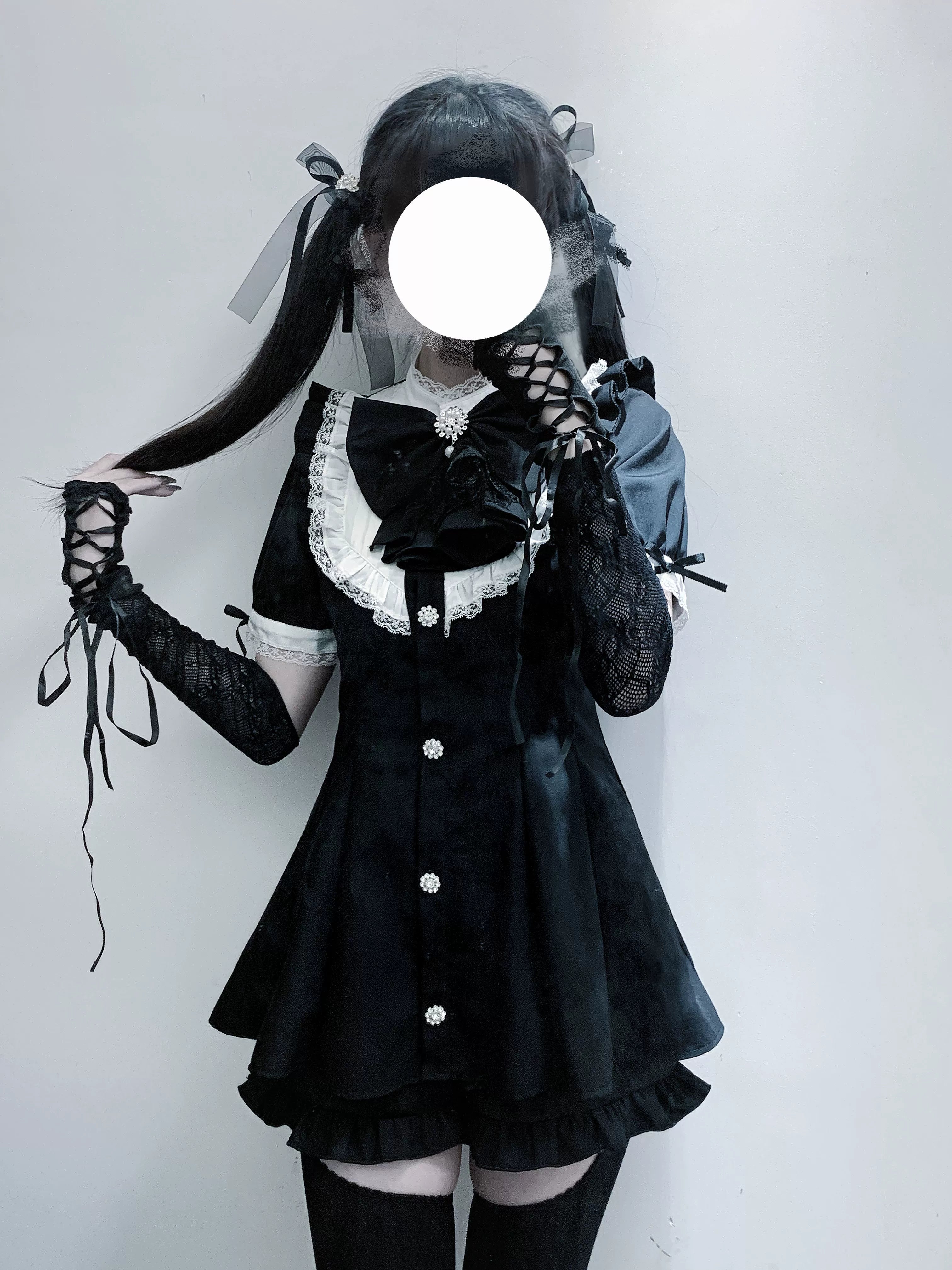 Jirai Kei black lace dress with jabot collar and puff sleeves worn by model with twin ponytails, showcasing gothic lolita aesthetic and ruffled chest details