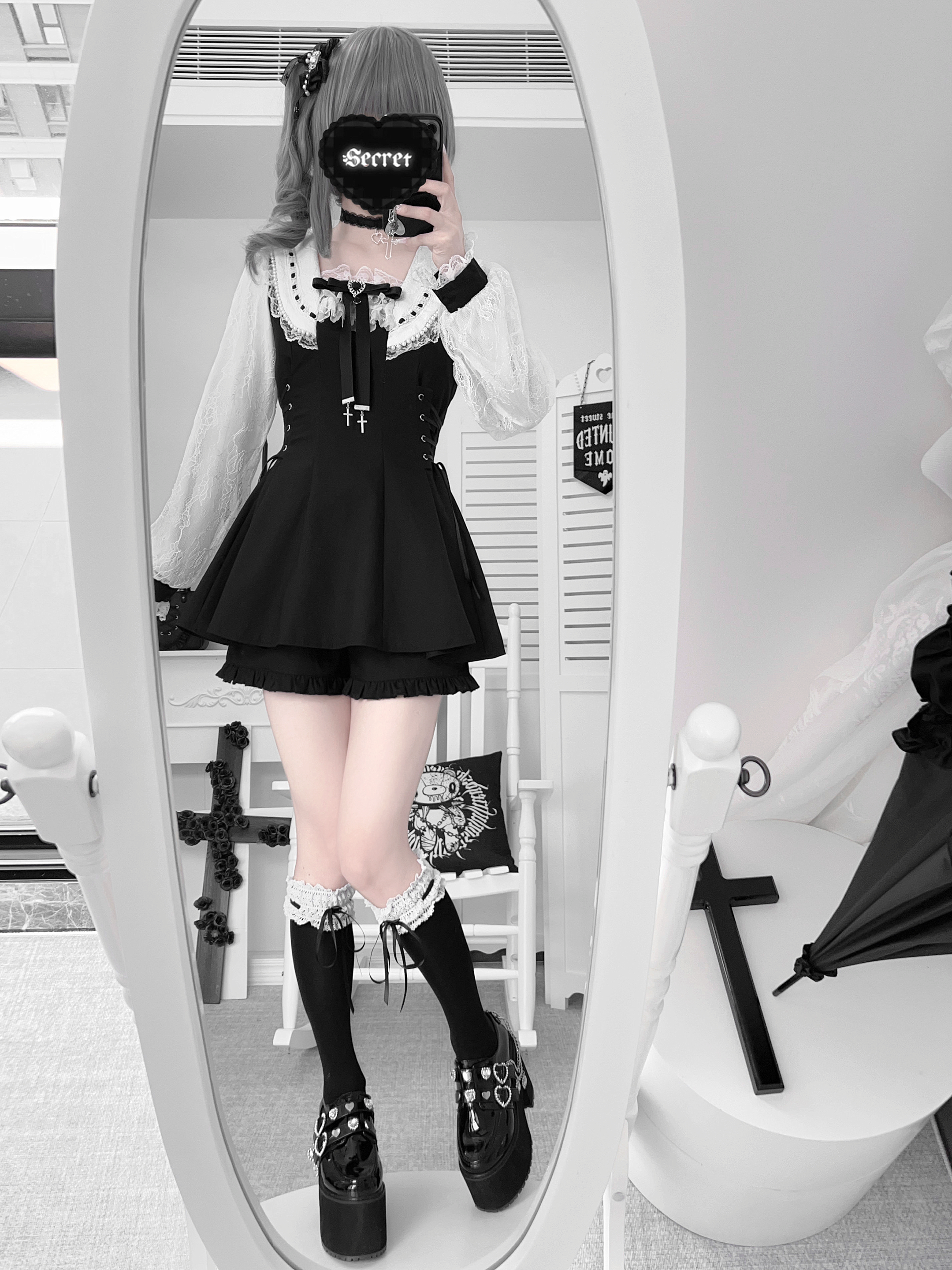 Model in solid black Jirai Kei ensemble with cropped ruffled shorts platform shoes ruffled socks full-length mirror gothic styling