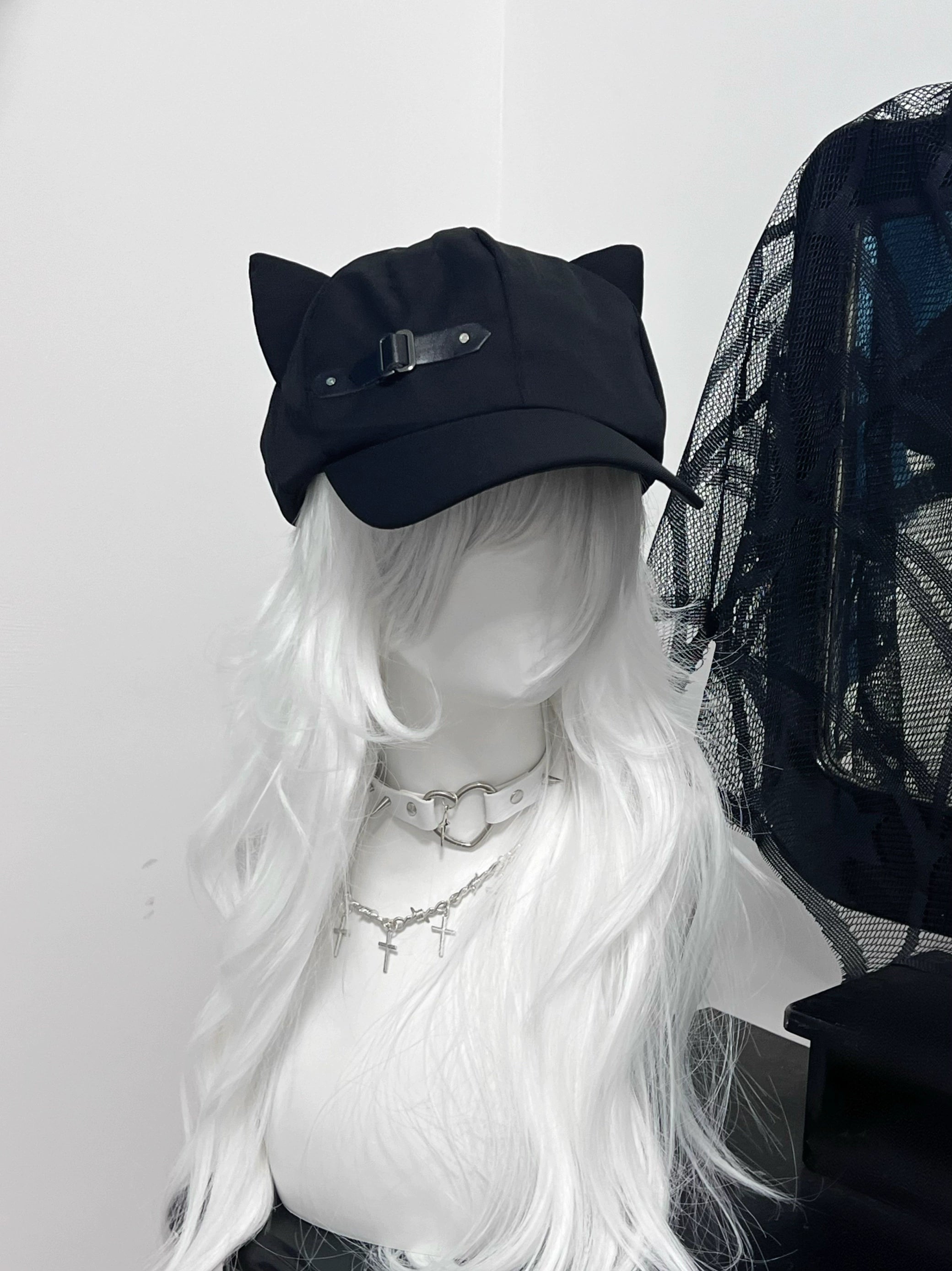 Black cat ear peaked beret cap with leather buckle detail, front oblique angle view on gothic mannequin with white curly hair, Jirai Kei fashion accessory