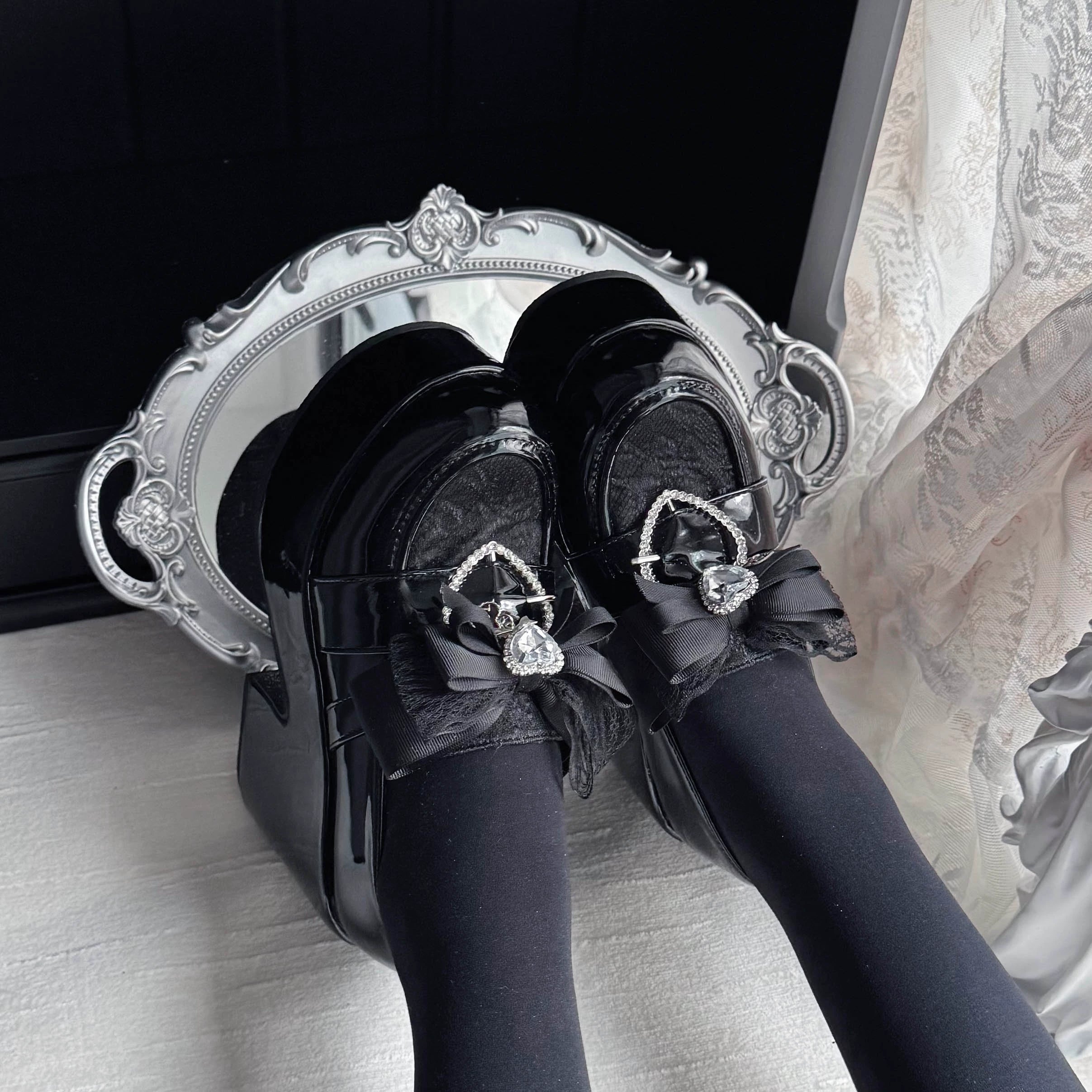 Black Jirai Kei Ryousangata platform loafers with lace toe cap and heart rhinestone bow detail, flat lay top-down view showing patent leather finish