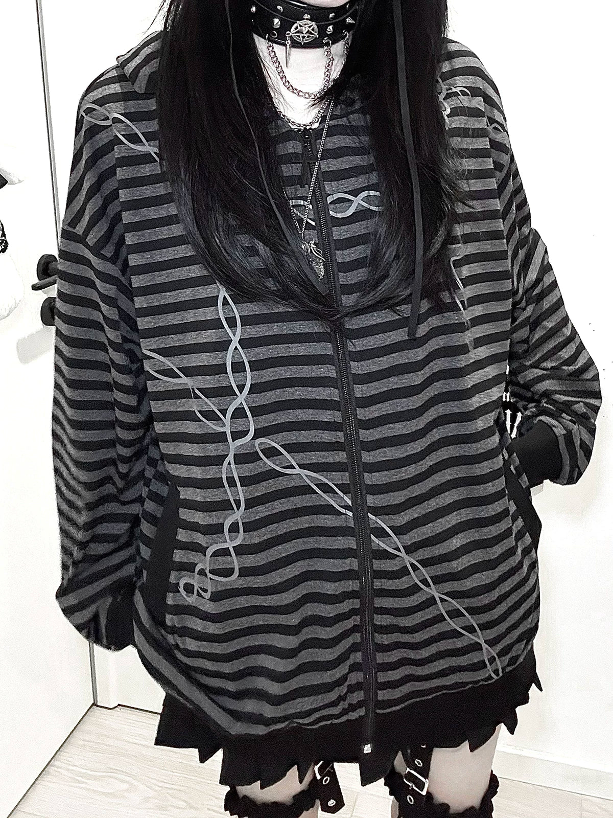 Gothic striped zip-up hoodie full-body three-quarter view female model with long black hair and layered necklaces, featuring ruffled hem and side pockets