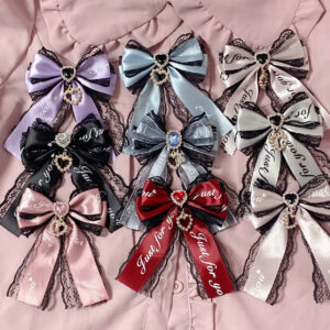 Jirai Kei ryousangata double bow hair clips collection flat lay featuring multiple color variants with rhinestone embellishments and lace trim accents on pink blouse background