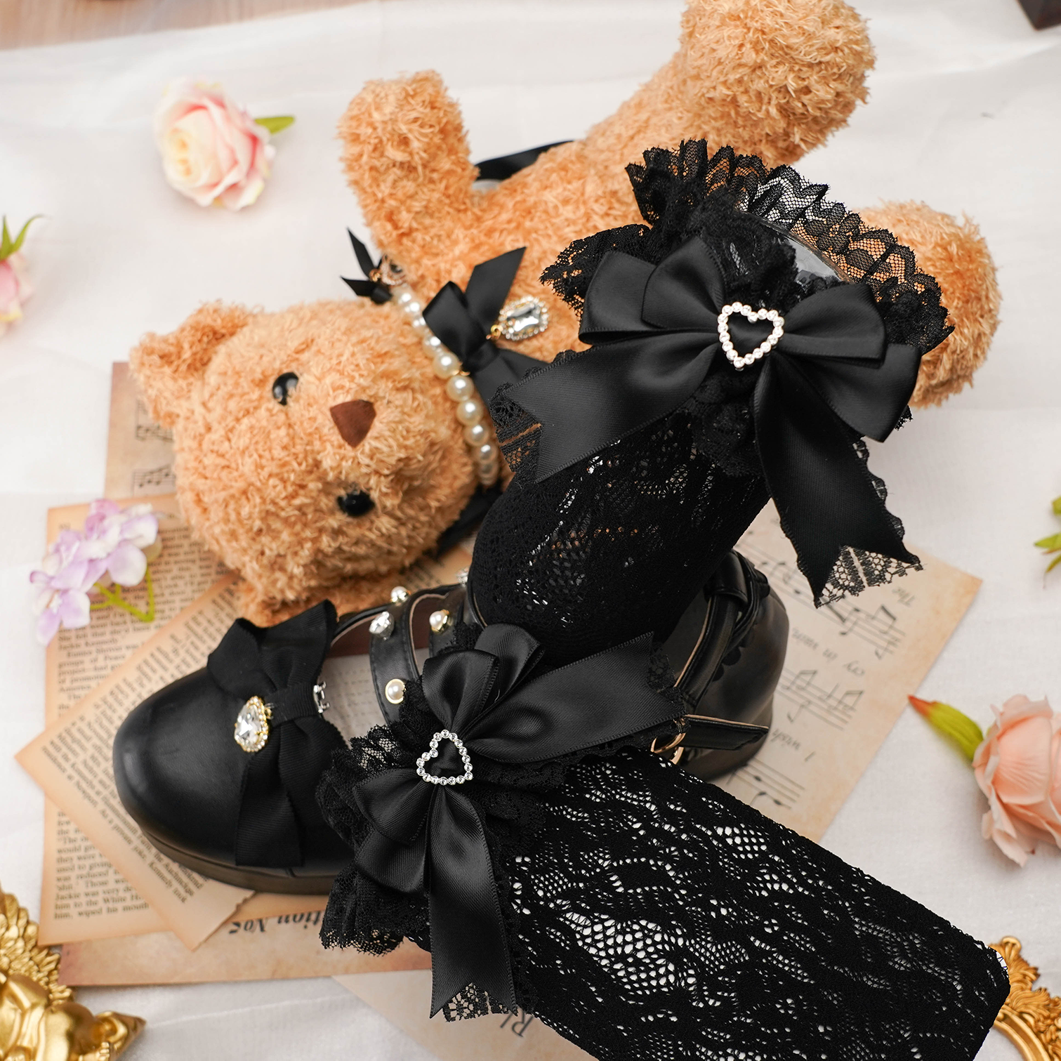 Flat lay styling of jirai kei lace socks with heart-shaped rhinestones and decorative satin bows arranged with vintage aesthetic props and flowers