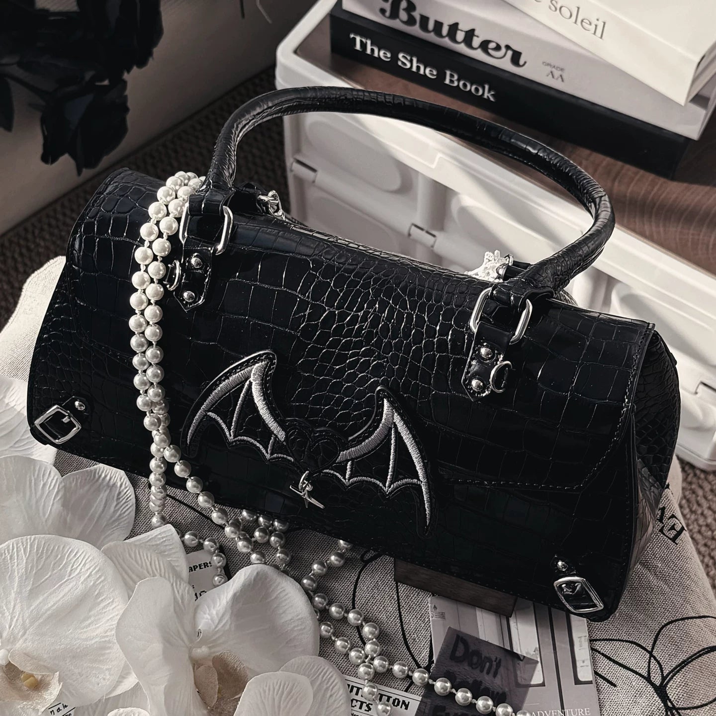 Bat-themed croc Jirai Kei itabag lifestyle shot showing daily use at coffee shop or social gathering alternative fashion accessory
