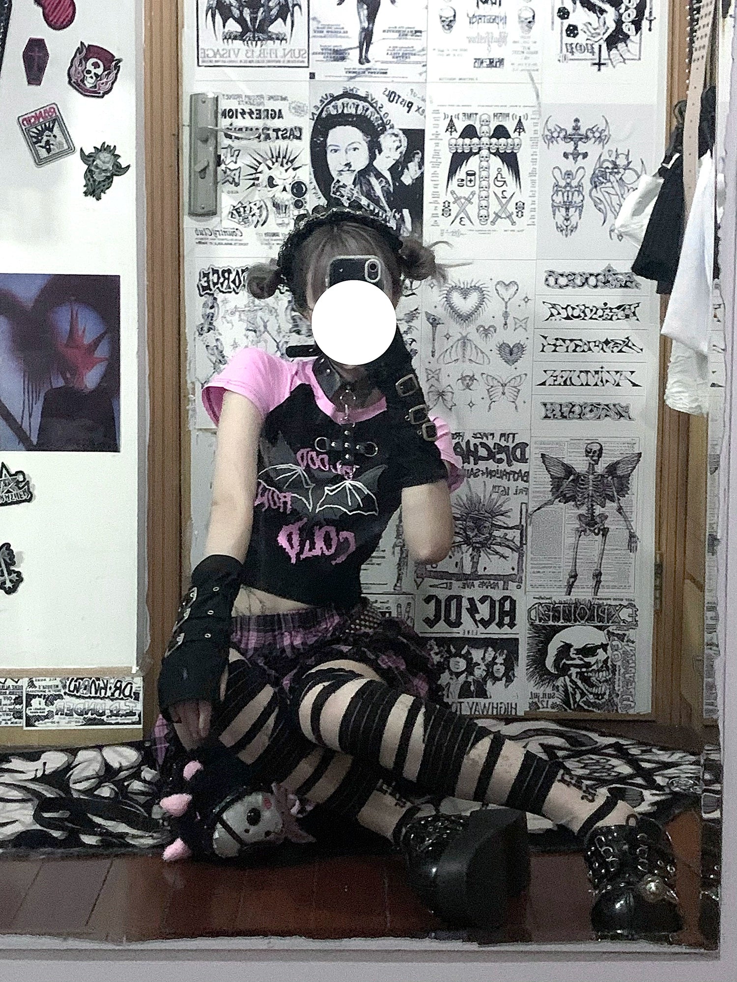 Pink-black plaid Jirai Kei ruffle skirt low-angle sitting view, punk model in sticker room with striped thigh-high wrap and platform boots