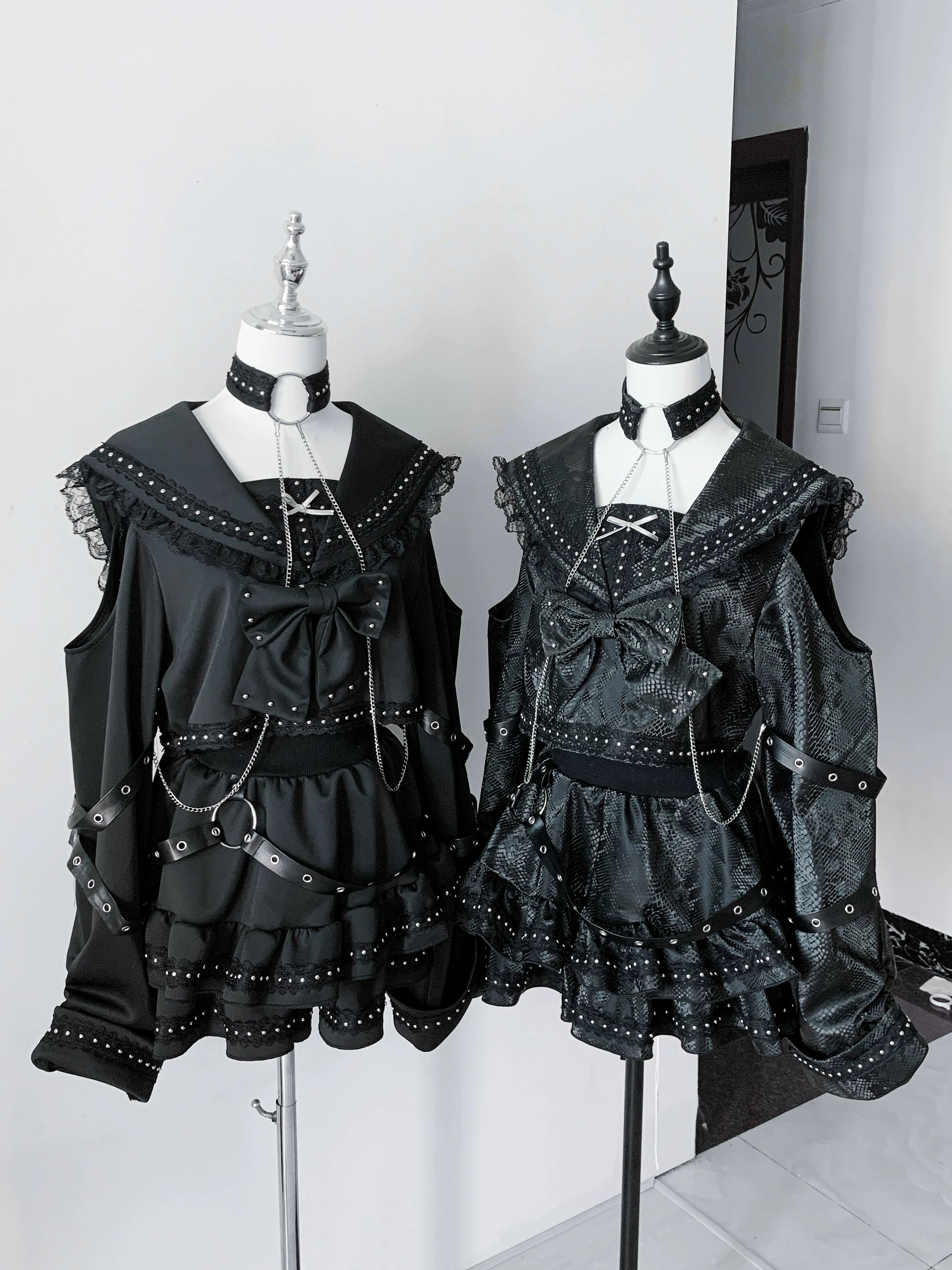 Two matching black gothic sailor outfit sets displayed on mannequins featuring sailor collar rivet details and tiered ruffled skirt construction
