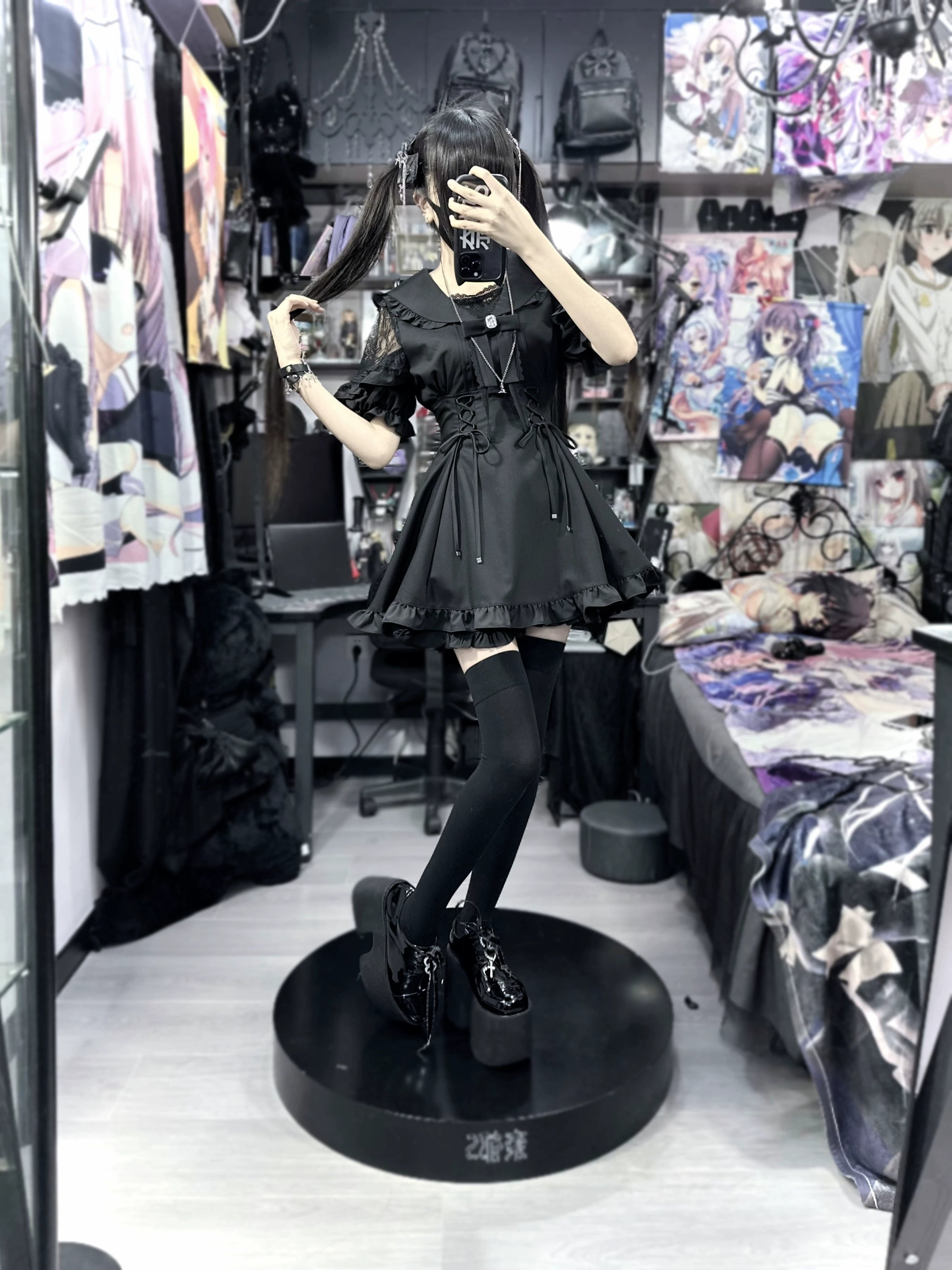Model wearing black gothic Jirai Kei sailor dress with thigh high socks and platform shoes side front view