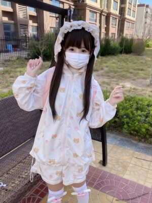 Side view of kawaii hooded sunscreen jacket with cat ear hood and pastel prints, three-quarter angle with pink bow-trimmed socks