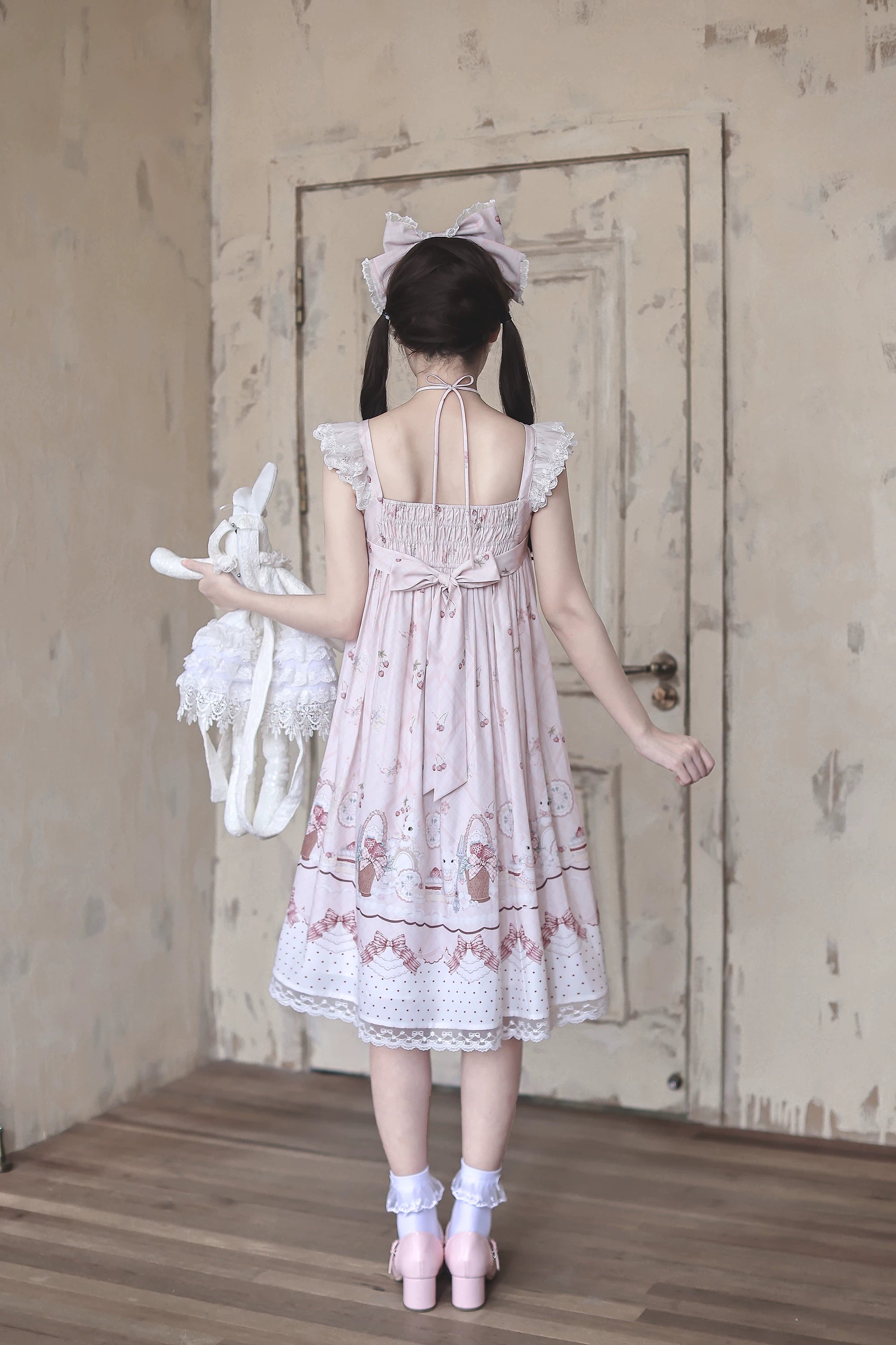 Back view of strawberry bunny Jirai Kei Lolita dress displaying back bow decoration shirring waist tie spaghetti straps and lace hem details