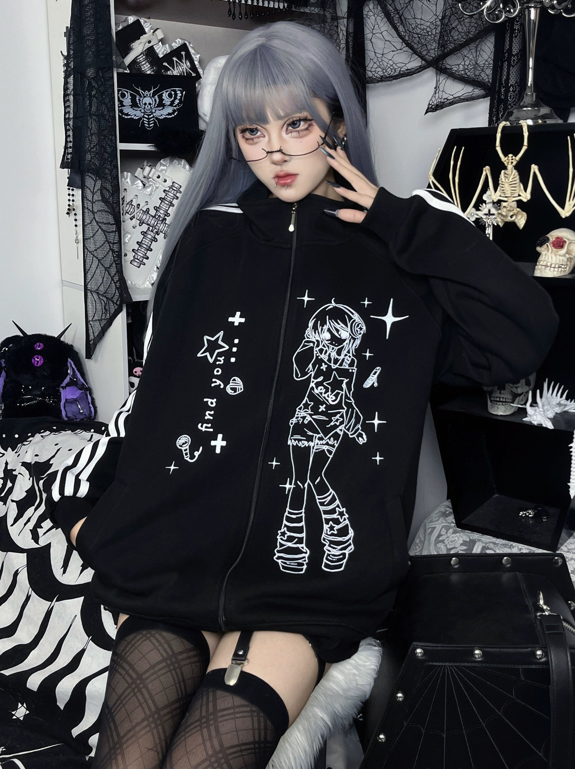 front-side seated view of black stand collar zip jacket with full anime character print and star accents throughout design