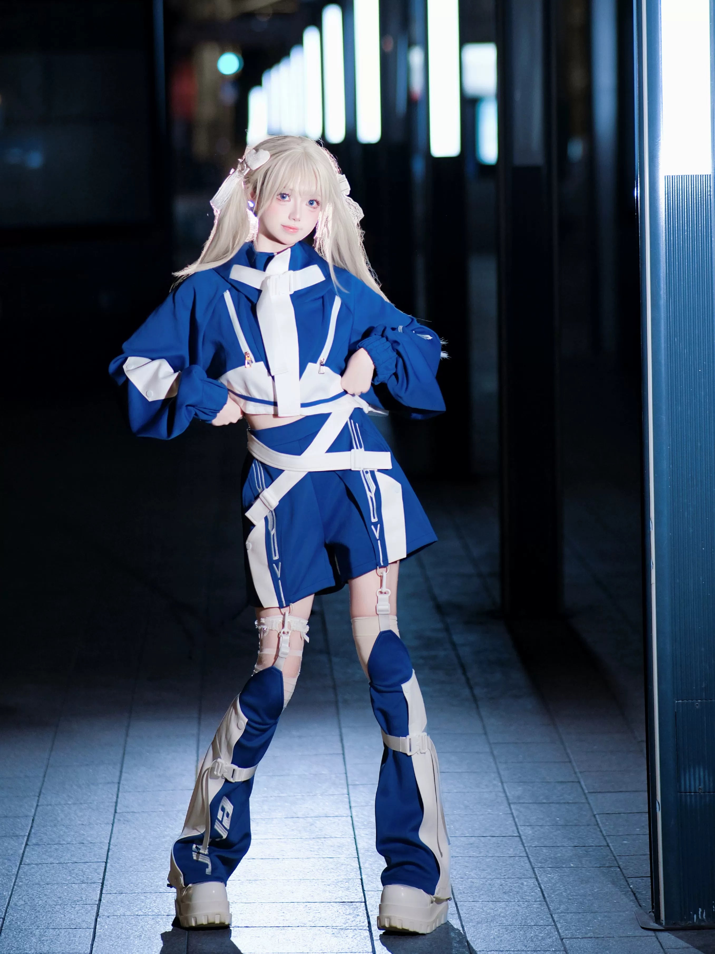 Blue white cyberpunk jirai kei cropped outfit set with strap harness cropped top shorts and leg guards on model hands on hips pose