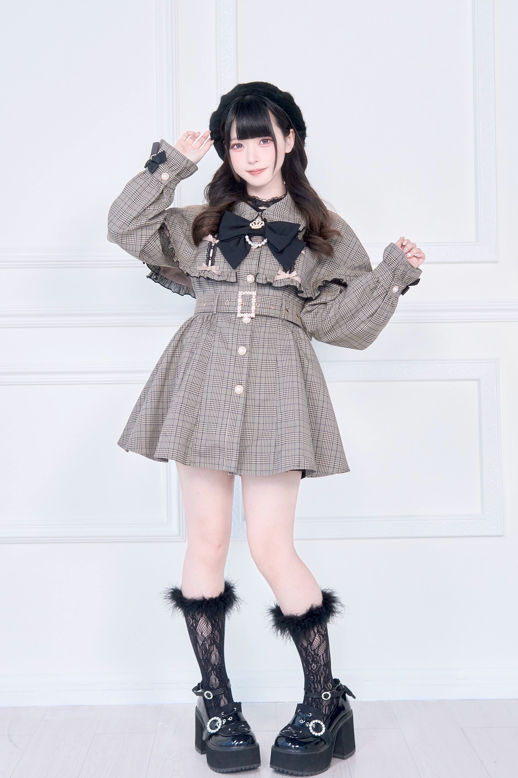 Black Jirai Kei cape trench coat front three-quarter pose with model salute showing bow tie fuzzy-trimmed lace socks details