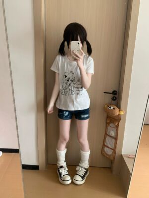 Jirai Kei white anime graphic t-shirt front view on model wearing twin-tails hairstyle in home doorway mirror selfie