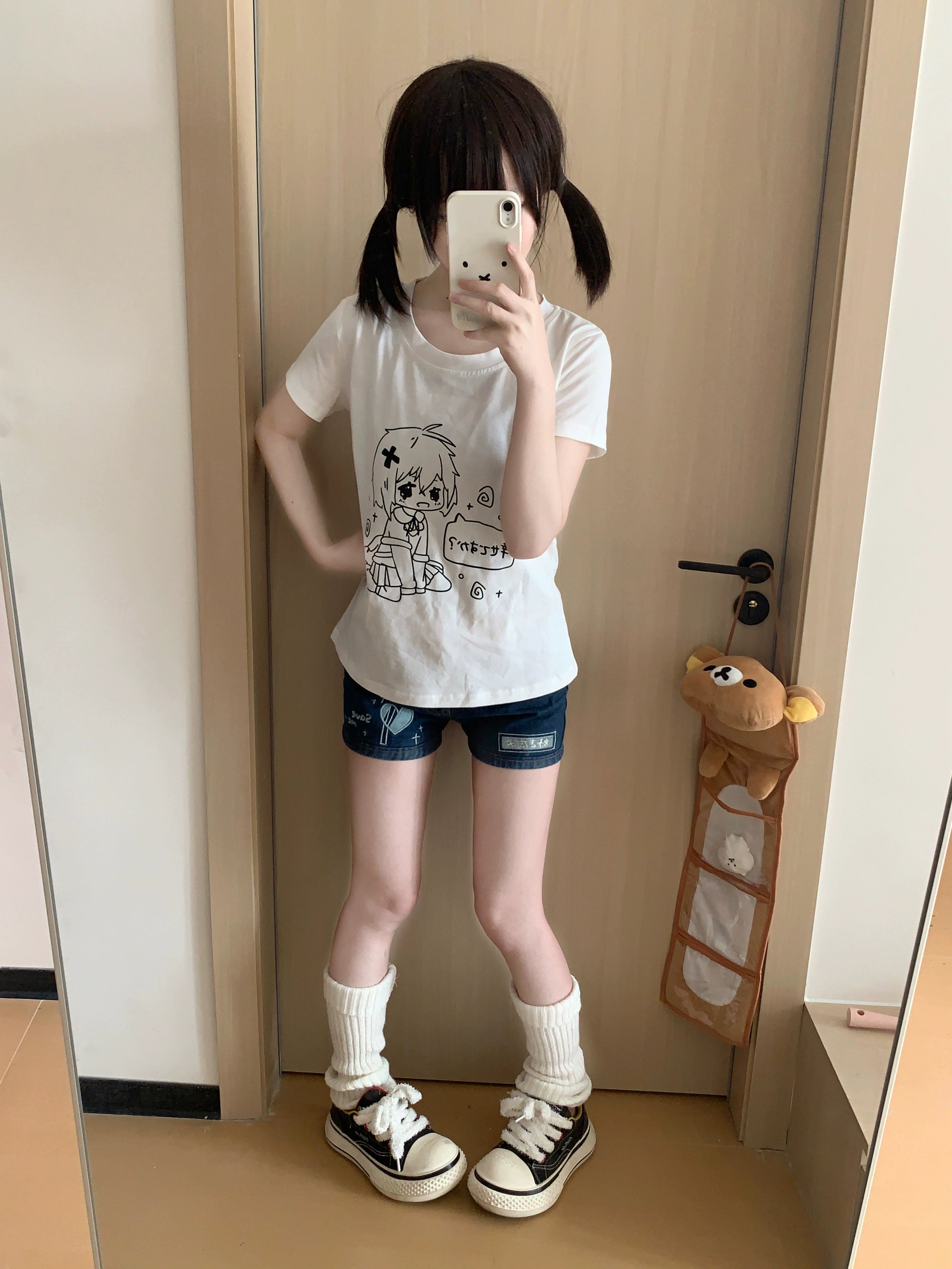Jirai Kei white anime tee flat lay on bed oblique view showing round neck short sleeves pink tag Japanese text
