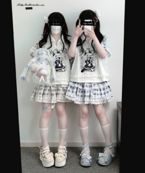 Jirai Kei two-piece fashion set featuring white polo collar top with anime character print and plaid ruffle skirt, modeled by twin girls in mirror selfie pose with platform shoes and white socks