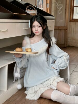 Soft blue off-shoulder one-piece sweater and white ruffled skirt set worn by model in indoor kitchen setting, demonstrating relaxed comfortable fit and romantic aesthetic
