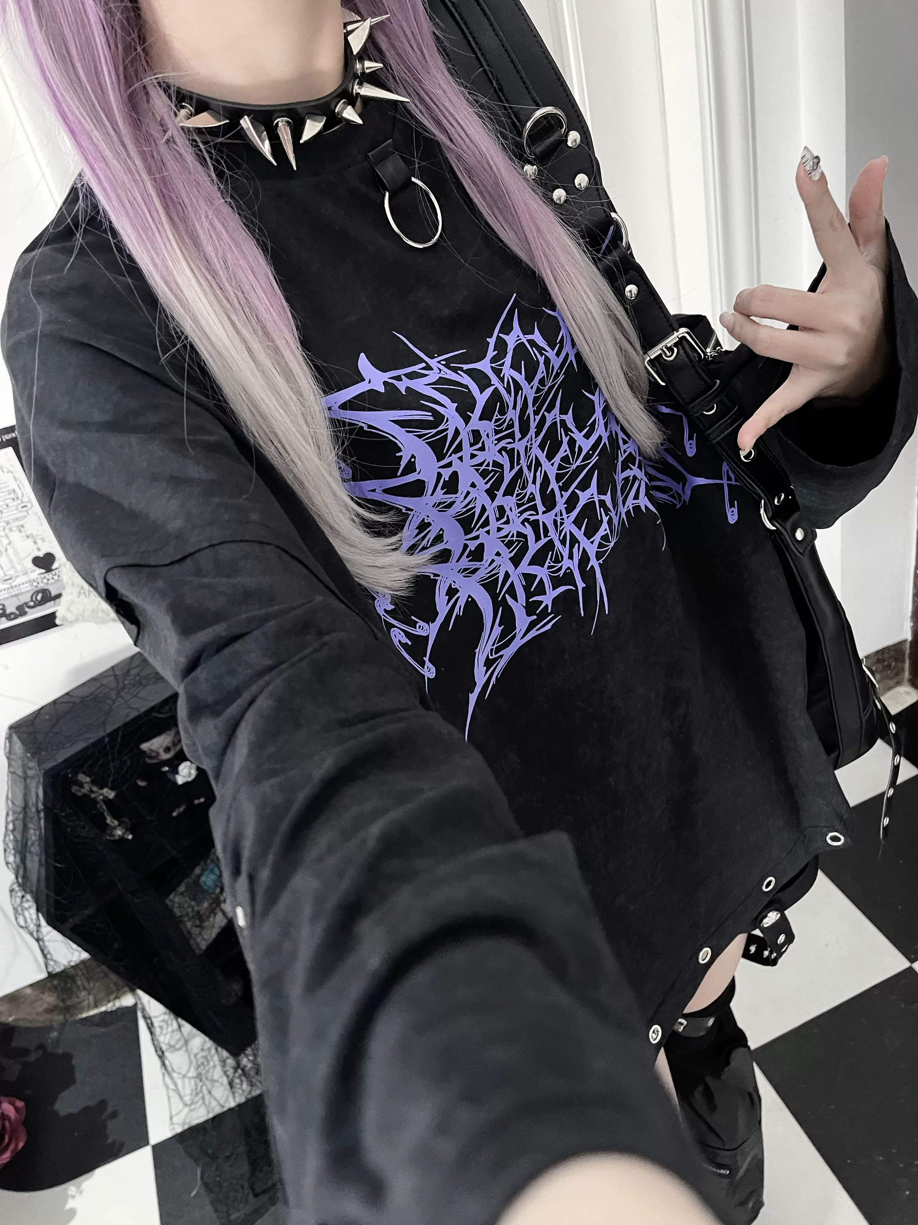 Model wearing black jirai kei oversized long-sleeve gothic tee with purple thorn cross print, styled with ombre purple-gray hair and spiked choker for dark subculture aesthetic