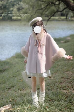 Back view of pink wool-blend cape cloak with white ruffle skirt, beret, and leg warmers, female model lakeside outfit