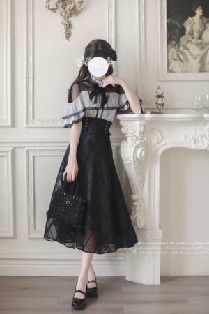 Jirai Kei two-piece outfit side angle, black handbag and bow necktie details visible in fireplace vintage room, cape blouse with adjustable back neckline