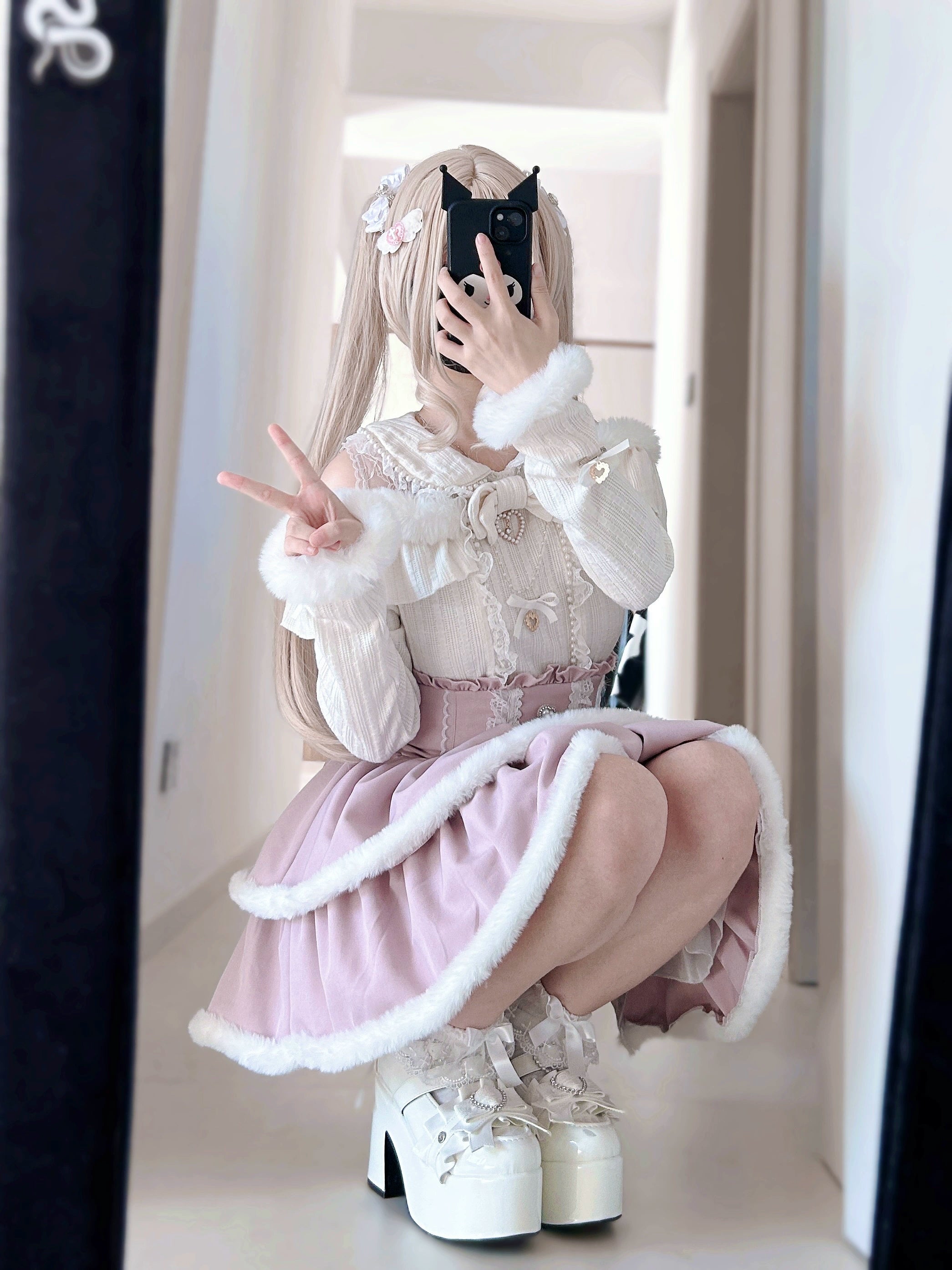 Model wearing beige Jirai Kei open-shoulder sweater with white plush trim and bow embellishments, squatting pose showing full outfit styling with platform shoes