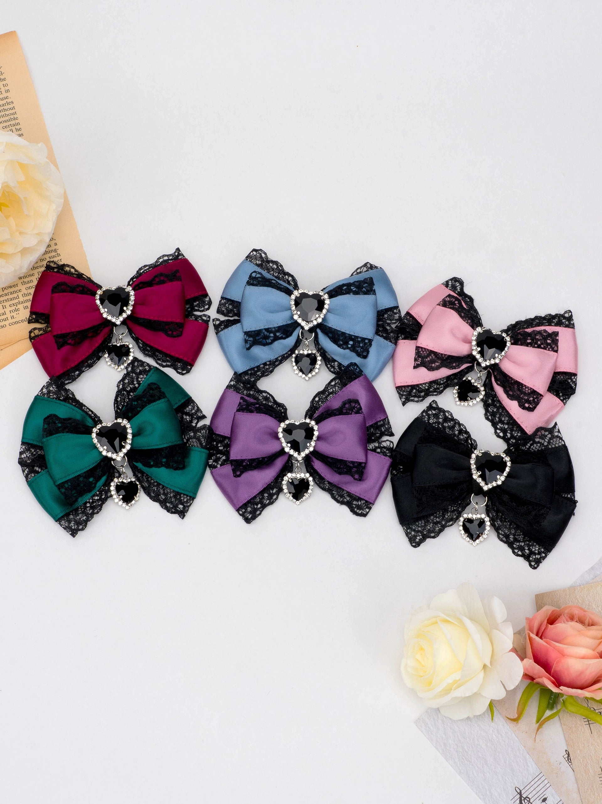 jirai kei butterfly knot bow hair clip color options arranged with artificial roses and vintage paper styling