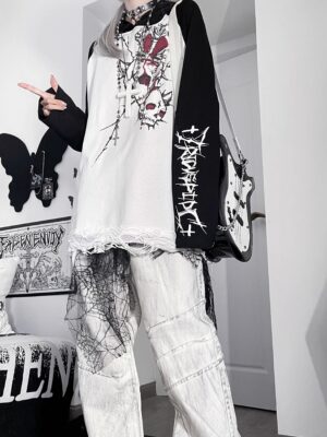Front view of black and white two-tone jirai kei gothic hoodie with skull graphics frayed hem and raglan sleeves on female model