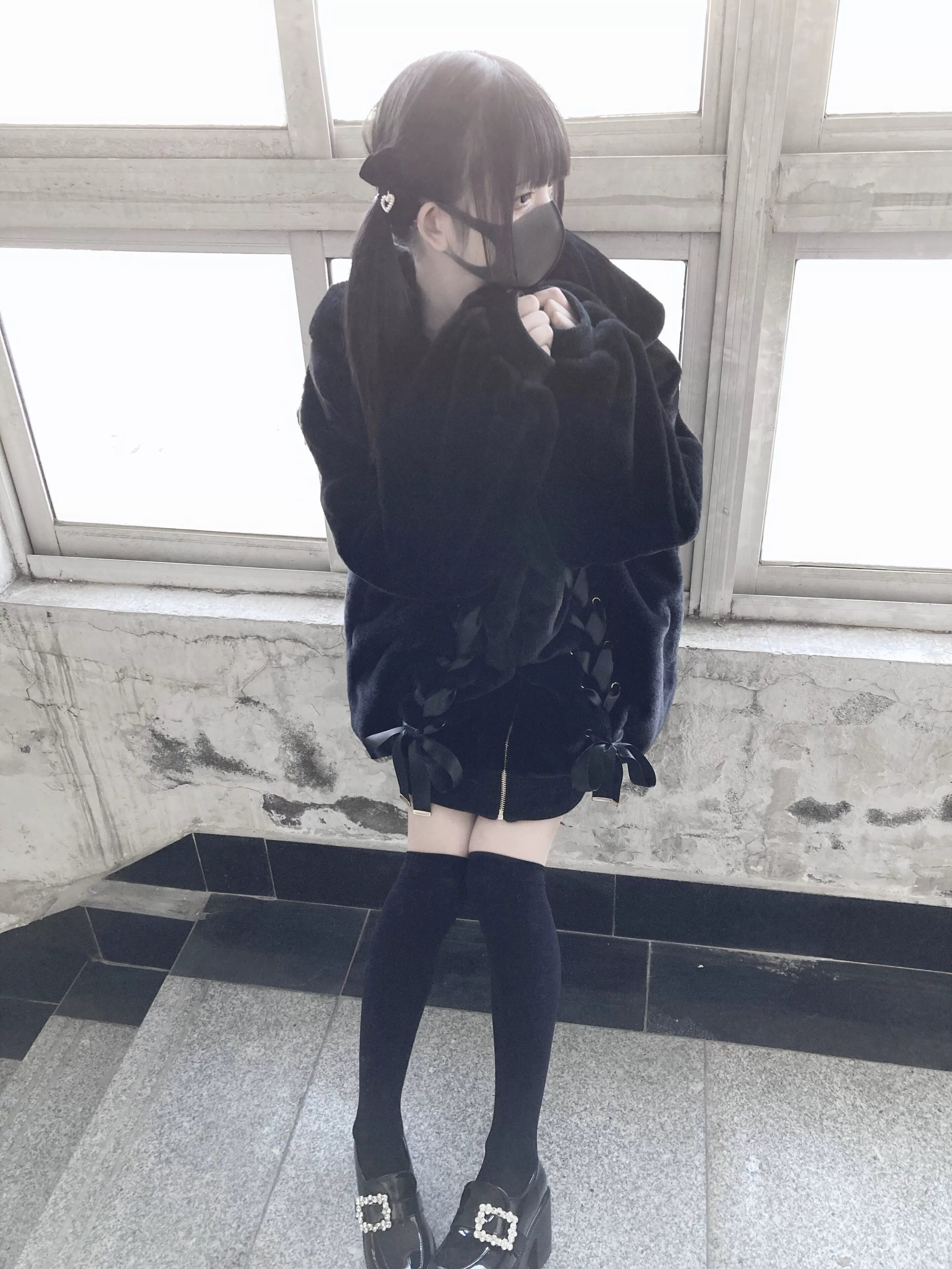 Black plush coat side-front view with bunny ear hood up showing decorative details and collar area