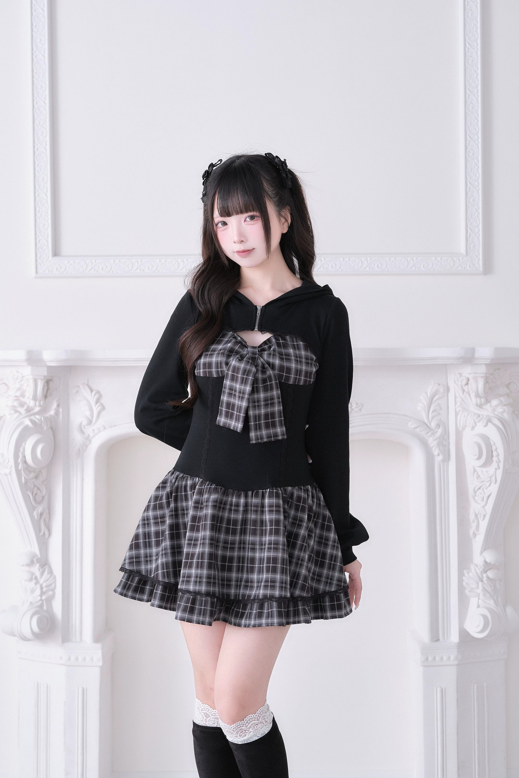 Plaid Jirai Kei hoodie one-piece dress front angle with bow accent and ruffled hem, model wearing black short socks