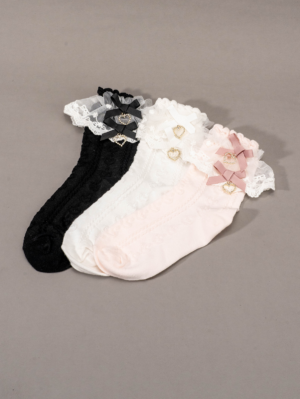 Overhead flat lay of three pairs of Jirai Kei lolita mid-calf socks with rhinestone heart charms lace ruffled cuffs and bow details on plain gray background